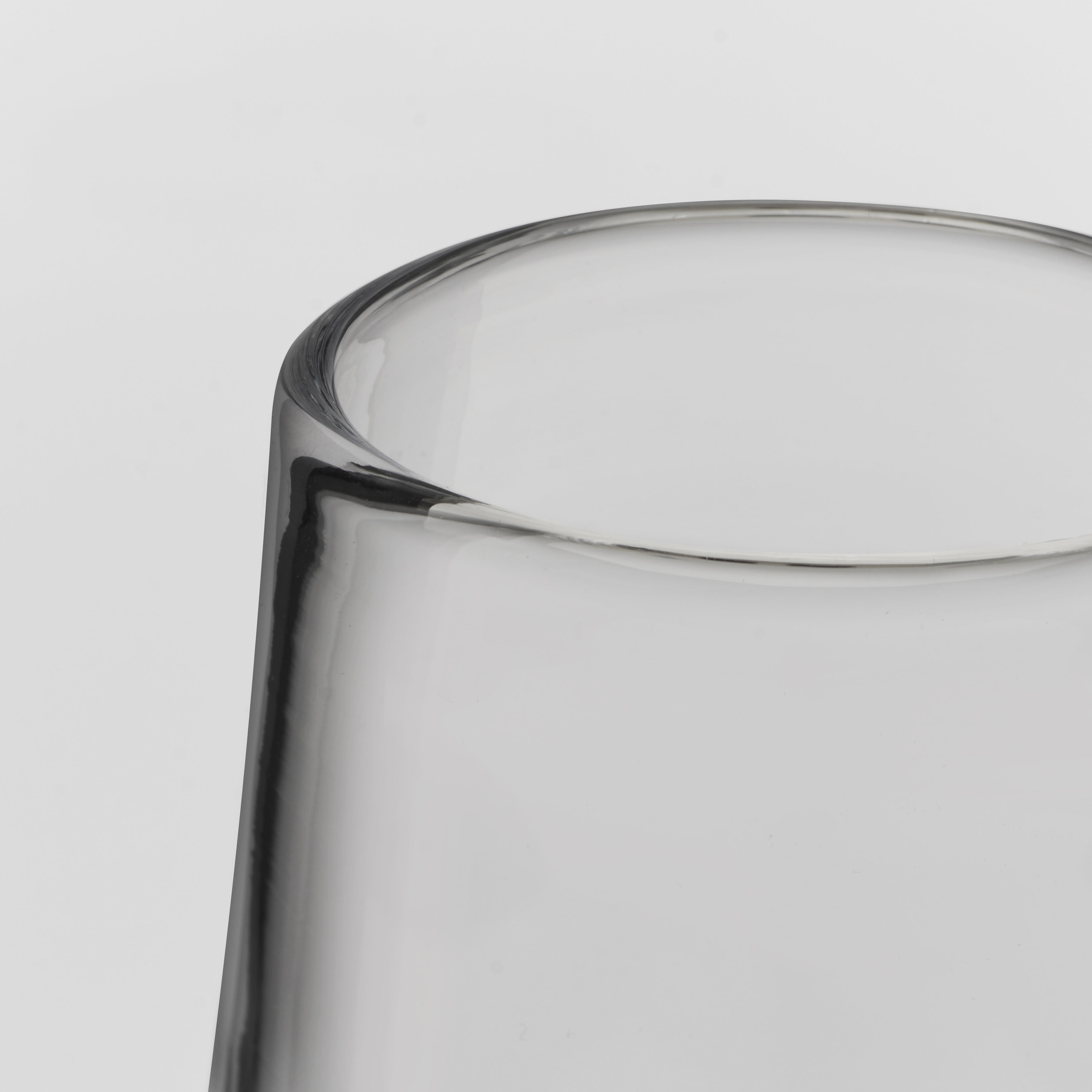 Close-up of a clear glass tumbler showing the rim and upper body against a light gray background.