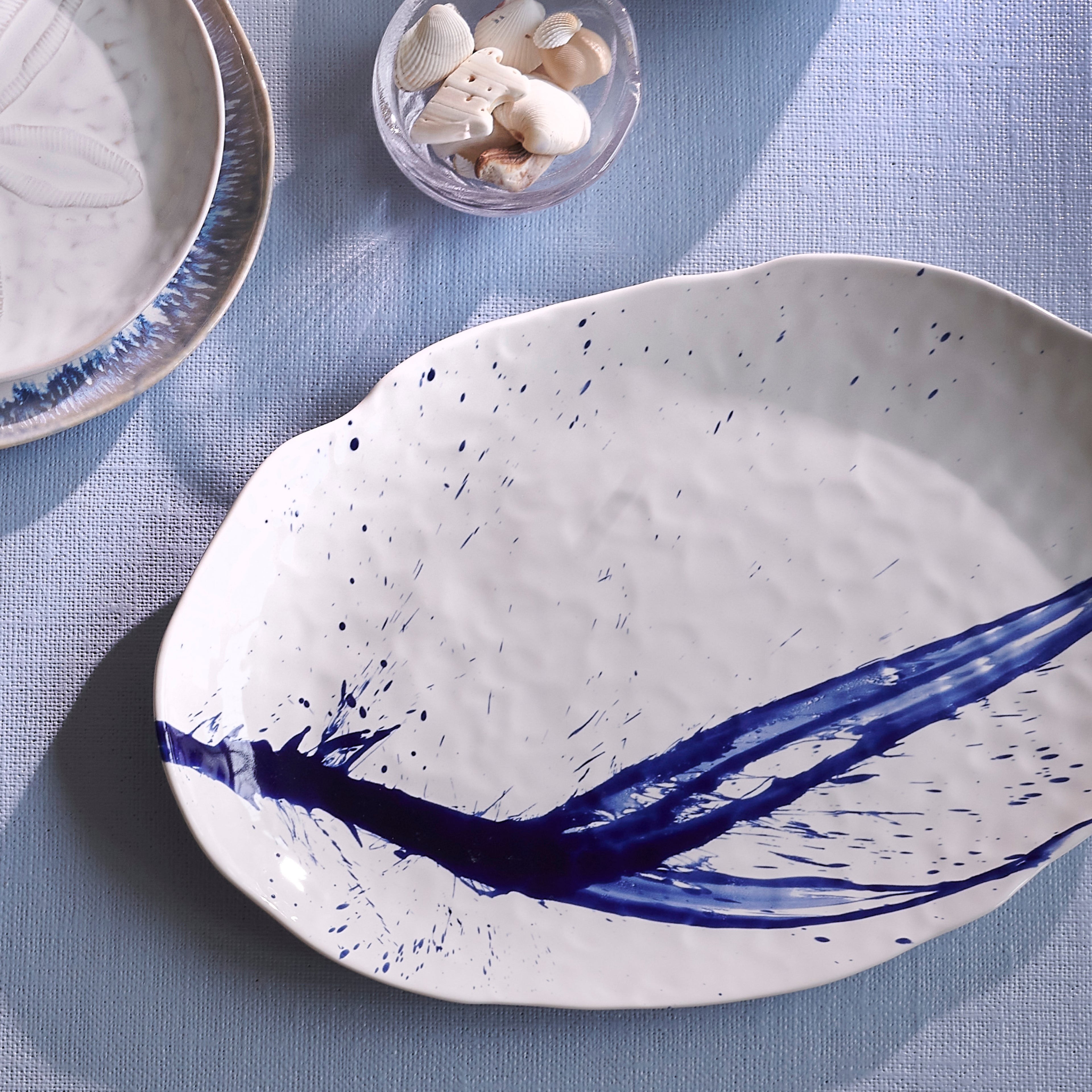 White oval platter with blue brushstroke design and speckled pattern.