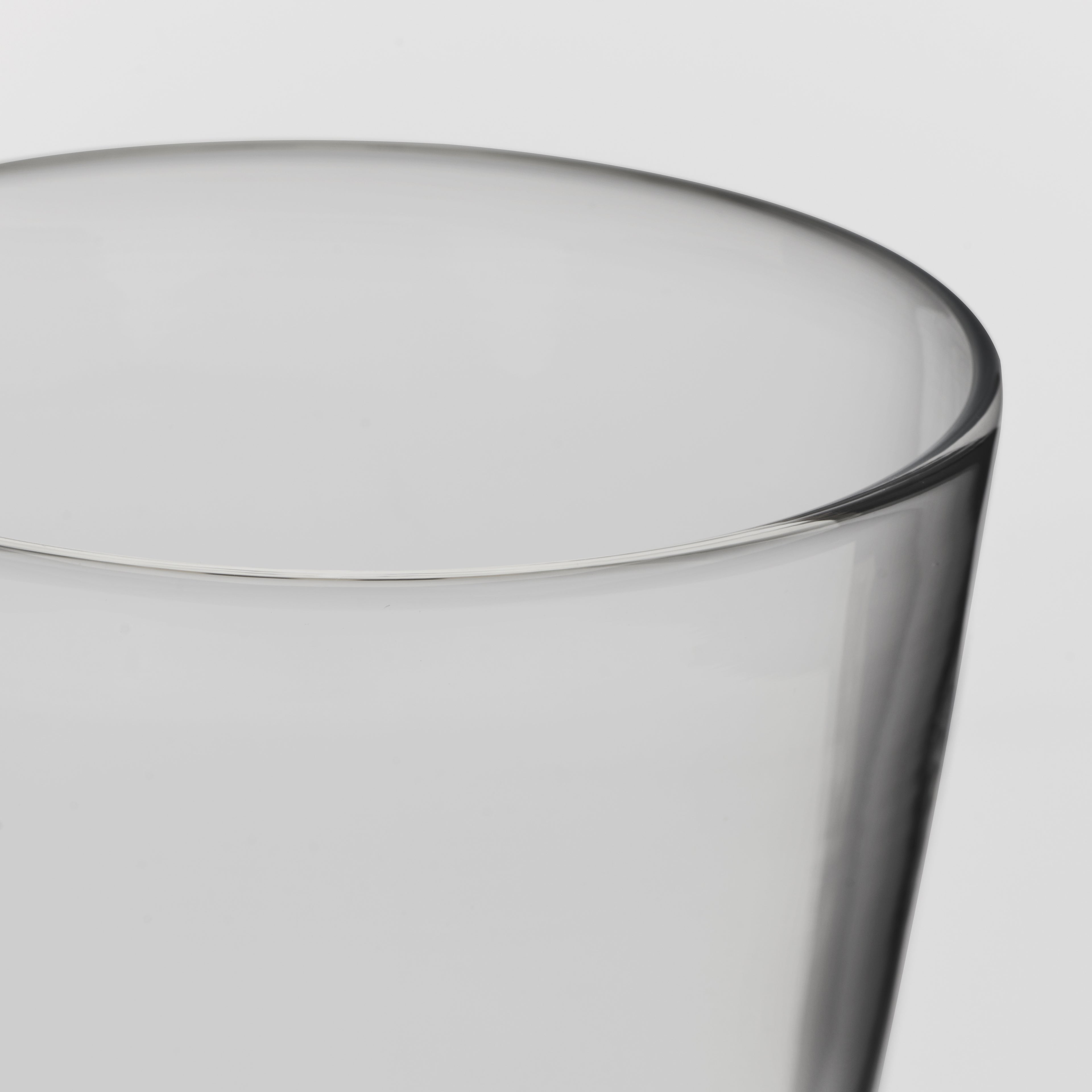 Close-up of a clear glass showing the rim and side against a light gray background.