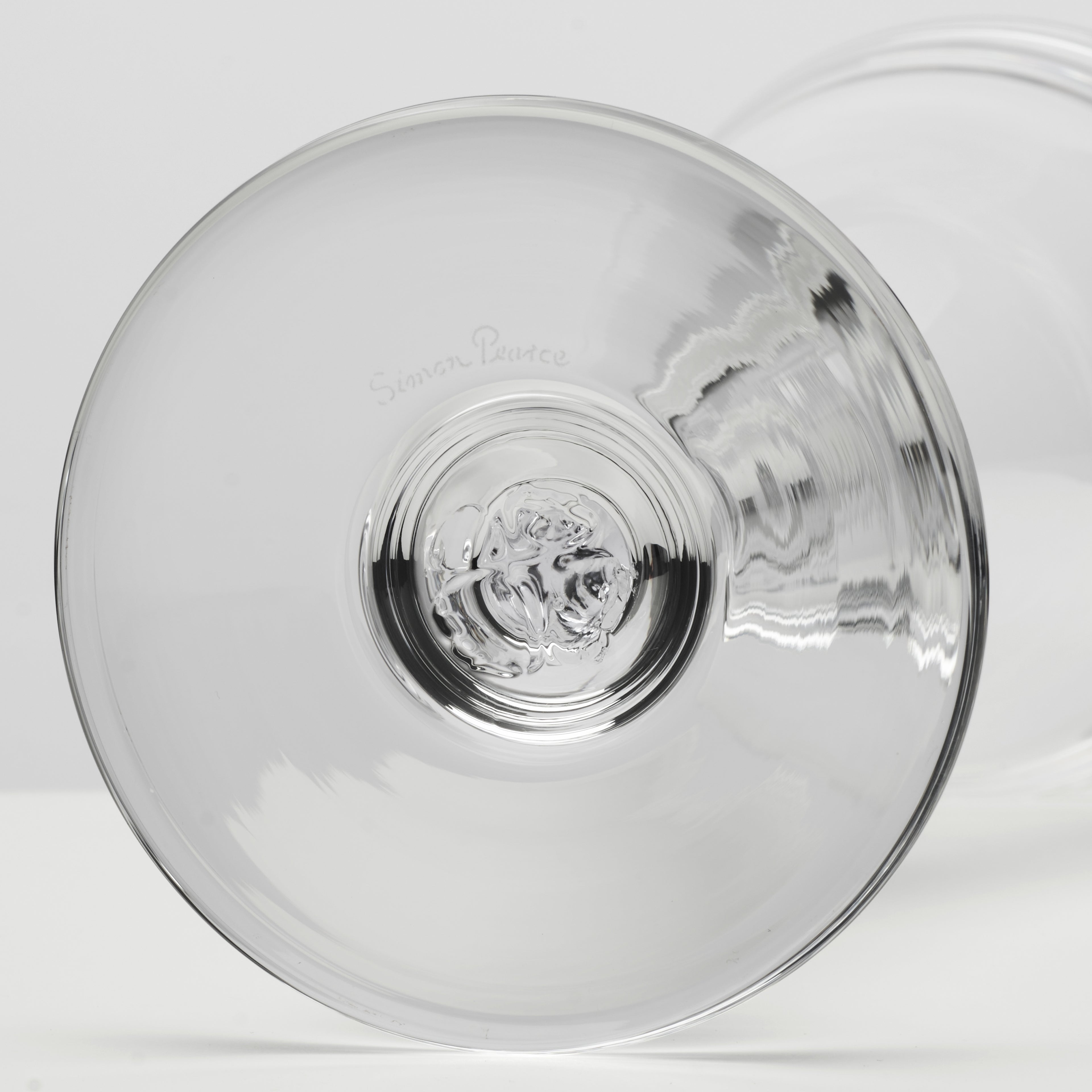 A close-up studio shot of a clear glass and subtle reflections on a light gray background.