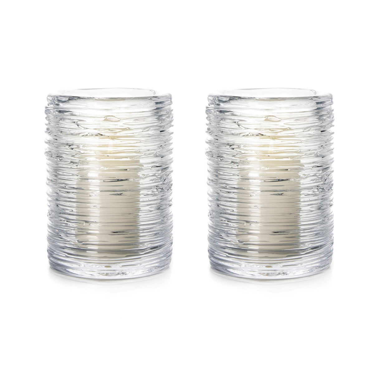 Two clear glass hurricane candles with textured horizontal ridges and cream-colored candles inside.