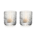 Two clear glass tealight holders with textured horizontal ridges and lit candles inside.