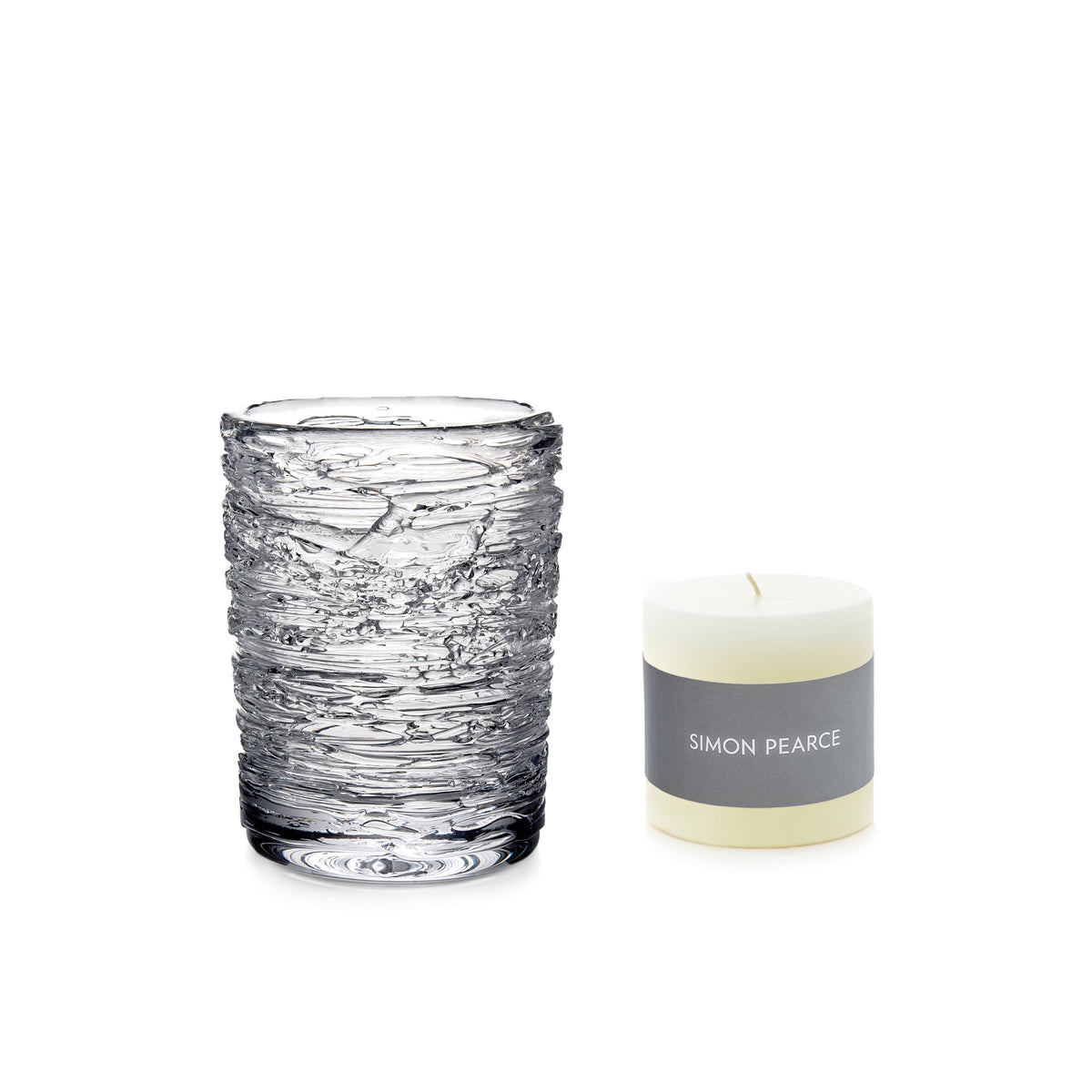 Clear textured glass votive holder with cream-colored candle labeled Simon Pearce in gray band.