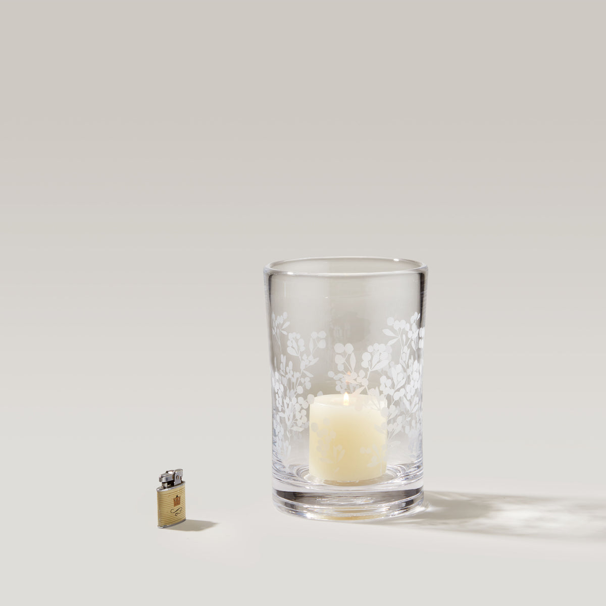 Large clear glass hurricane with white engraved berry and leaf design, holding a cream-colored candle.