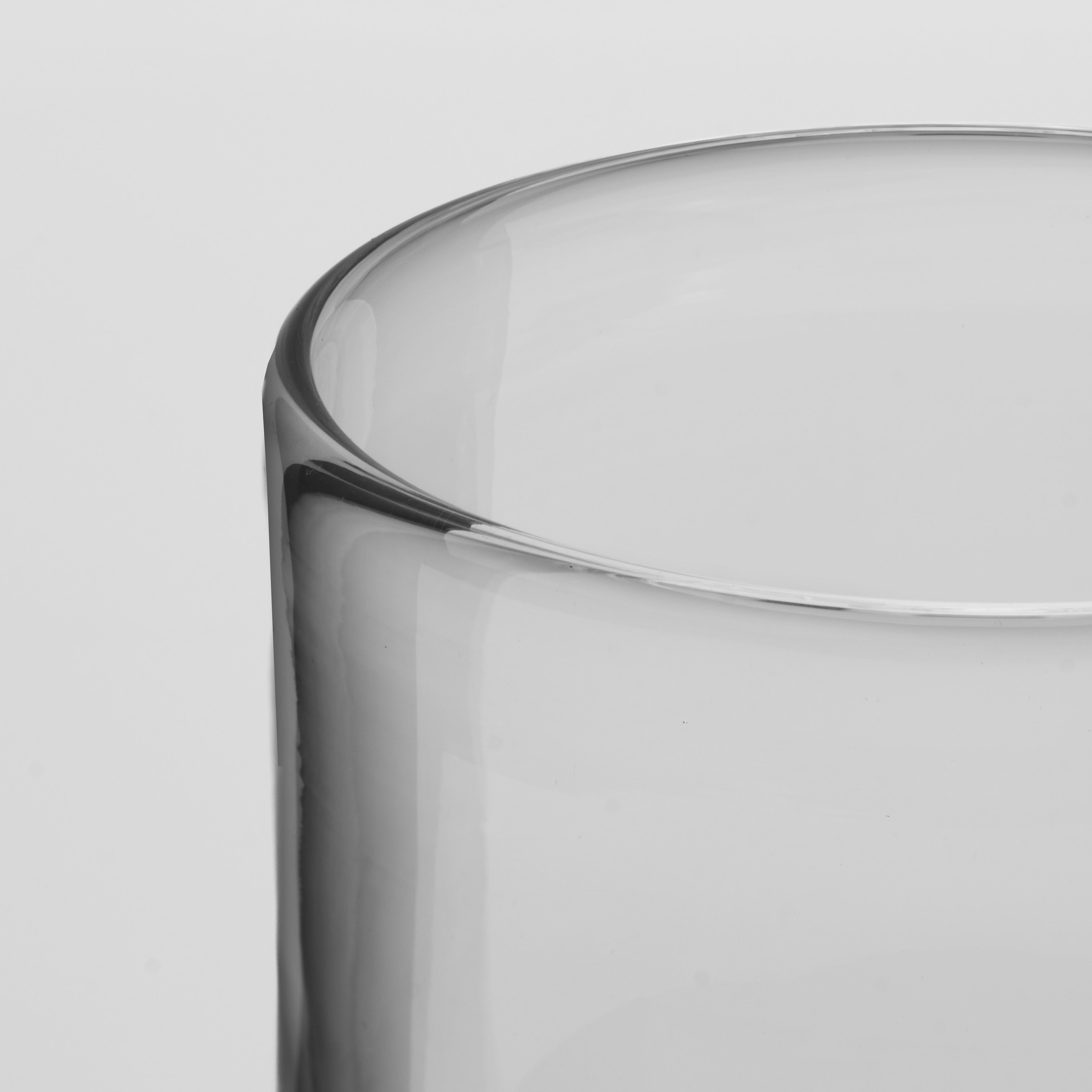 Close-up of a clear glass tumbler showing the rim and side profile against a light gray background.