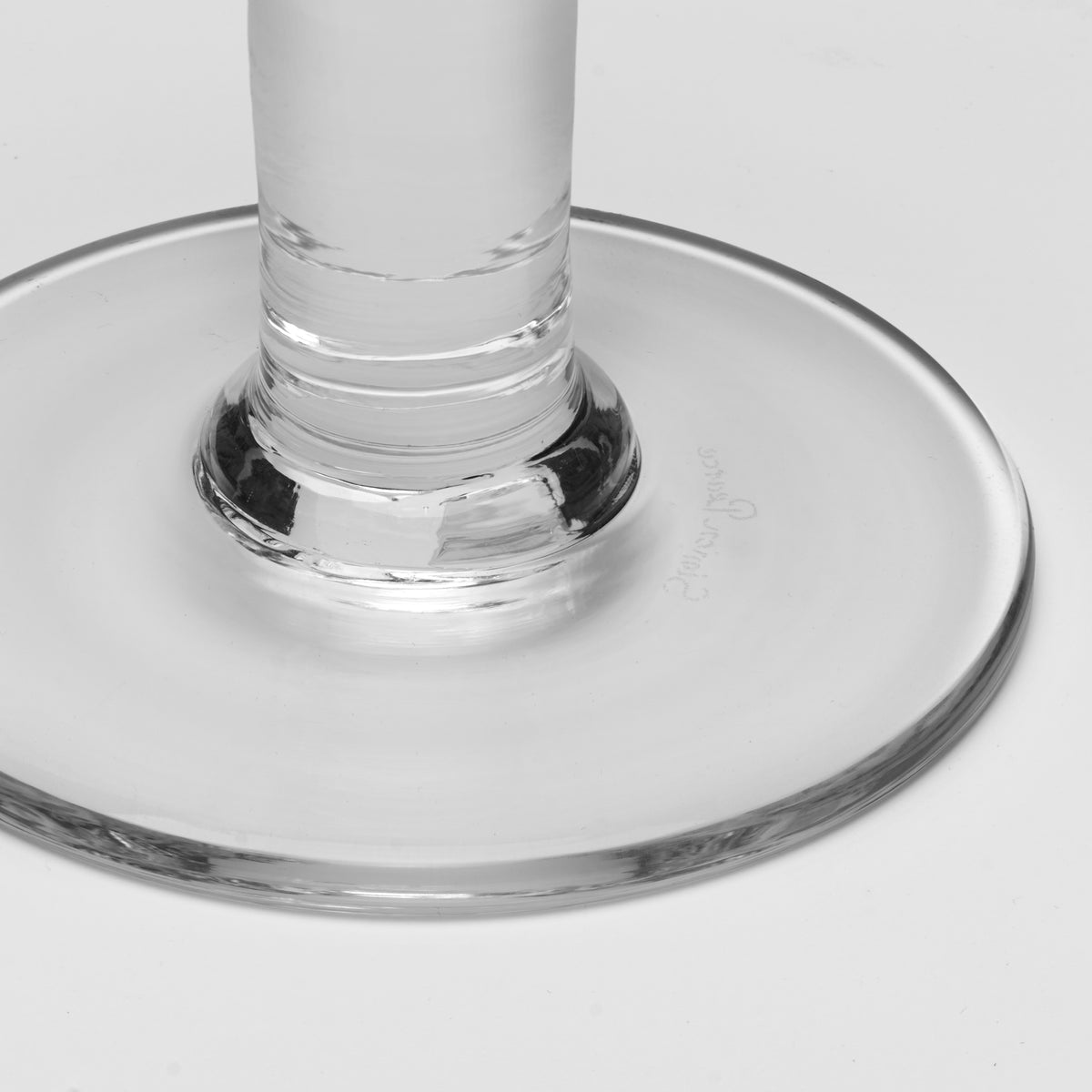 Close-up of a clear glass stem and circular base on a light gray background.