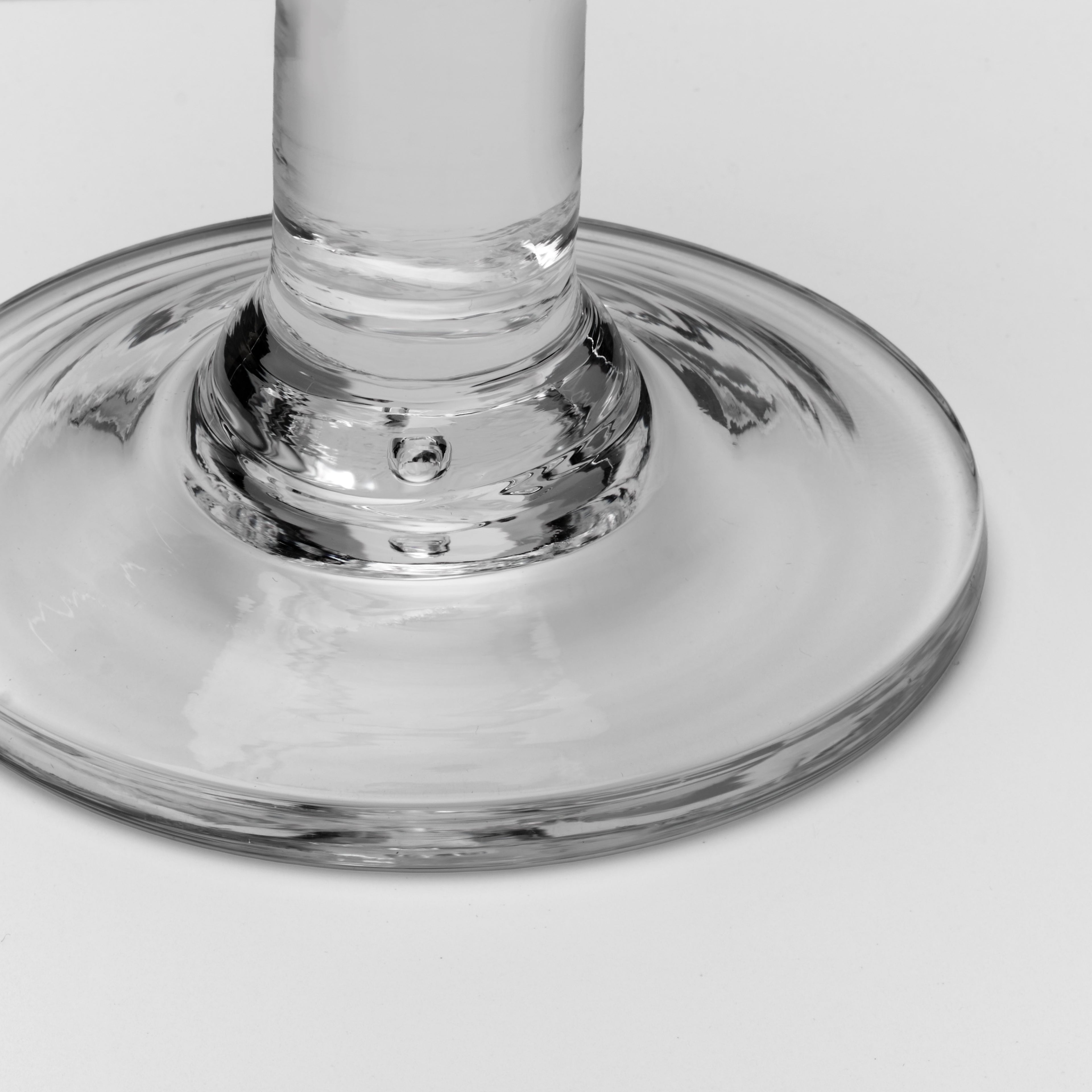 Close-up of a clear glass base and stem on a light gray background.