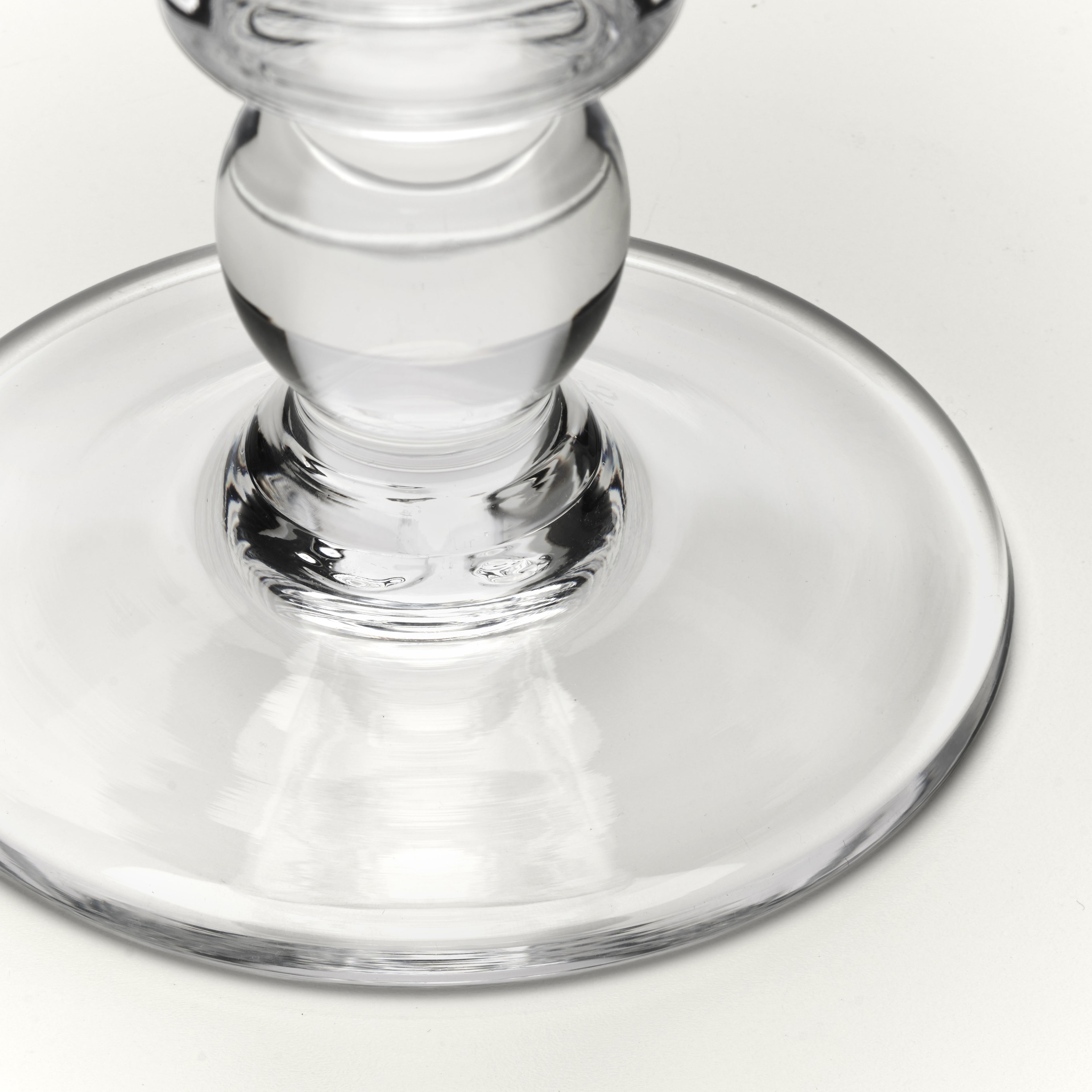 Close-up of a clear glass base and stem on a white background.