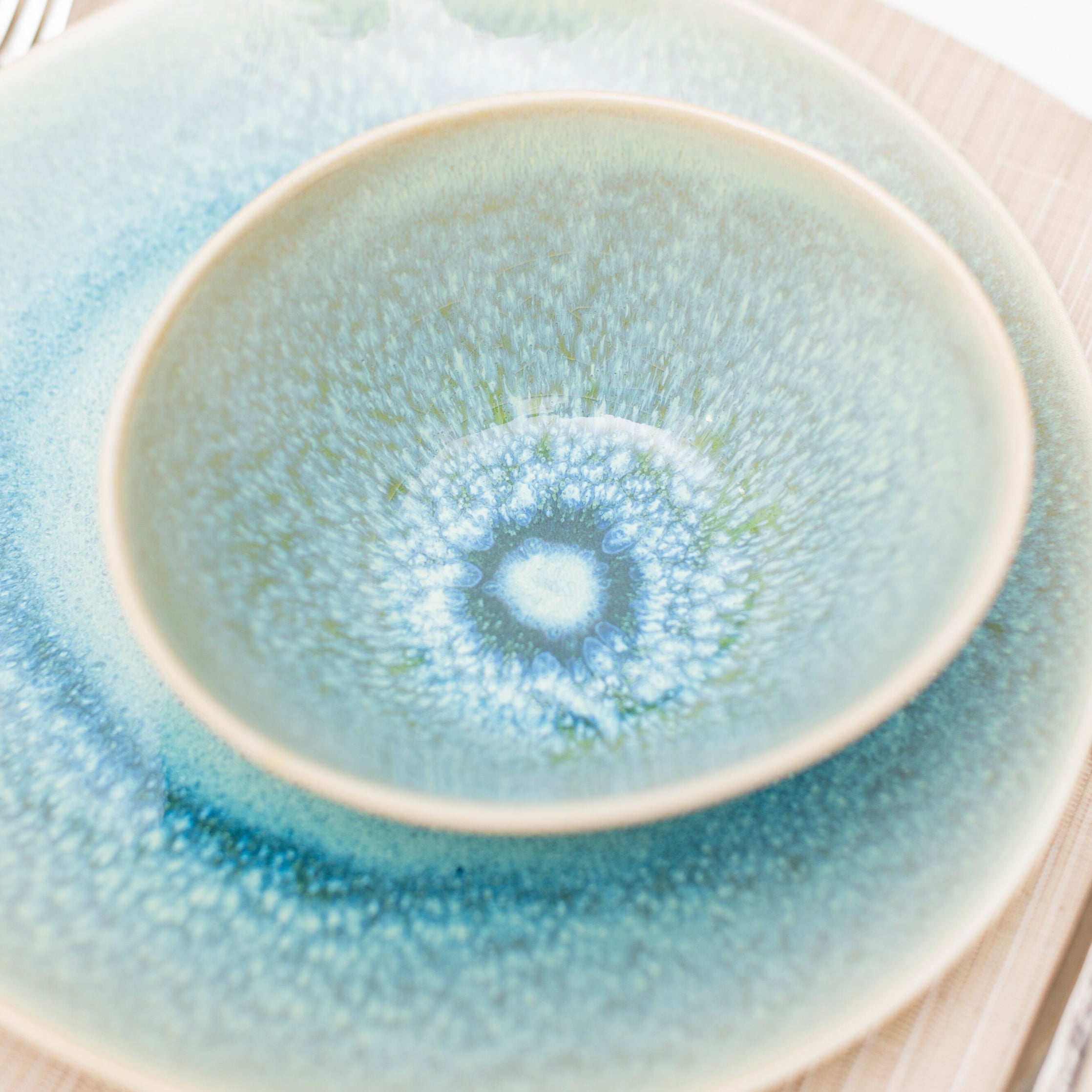 Two stacked bowls in pale green and blue with textured glaze and concentric circular pattern on interior.