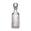 Clear glass decanter with vertical ribbed pattern and spherical stopper on white background.