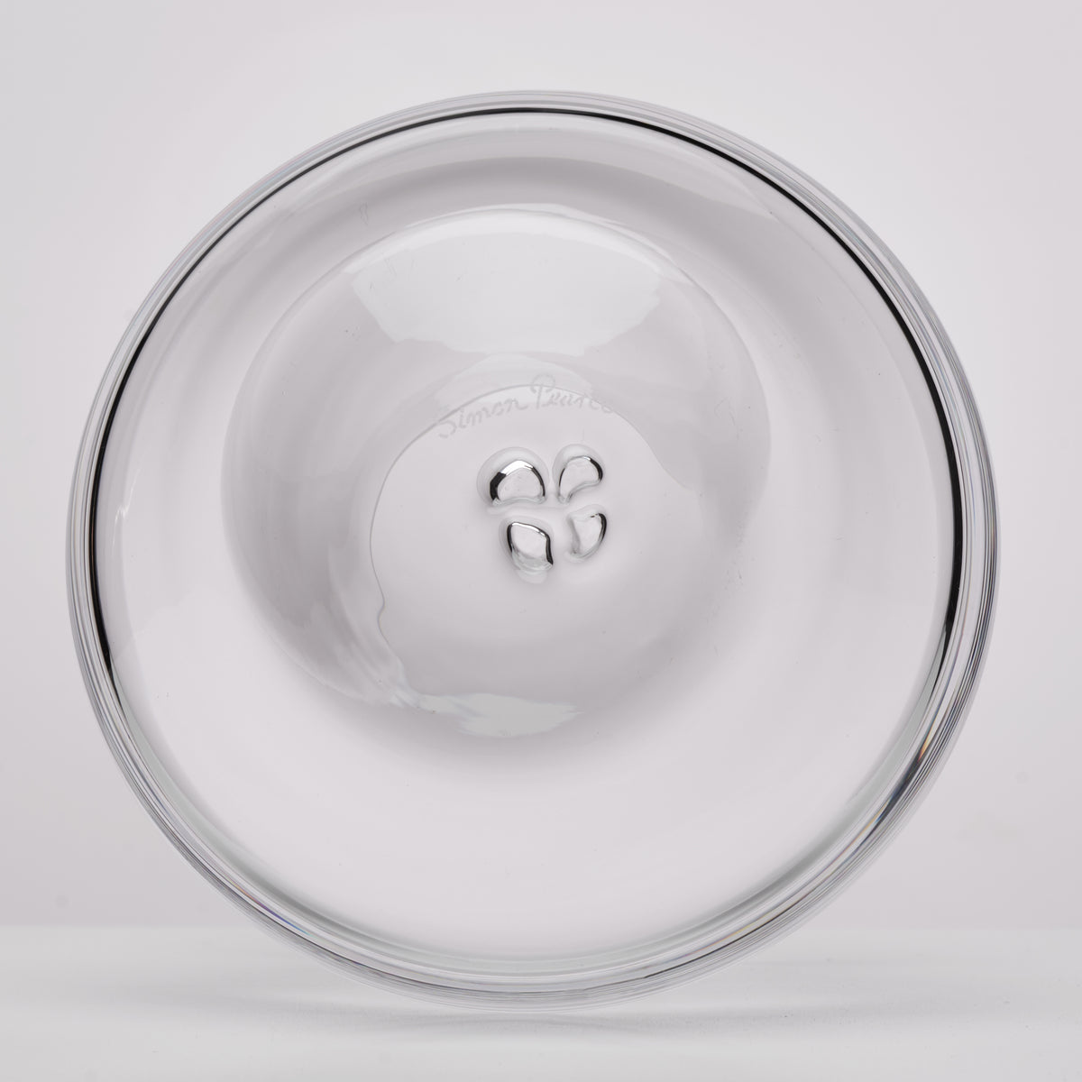 A clear glass bottom with a polished rim, photographed from directly above on a light gray background.