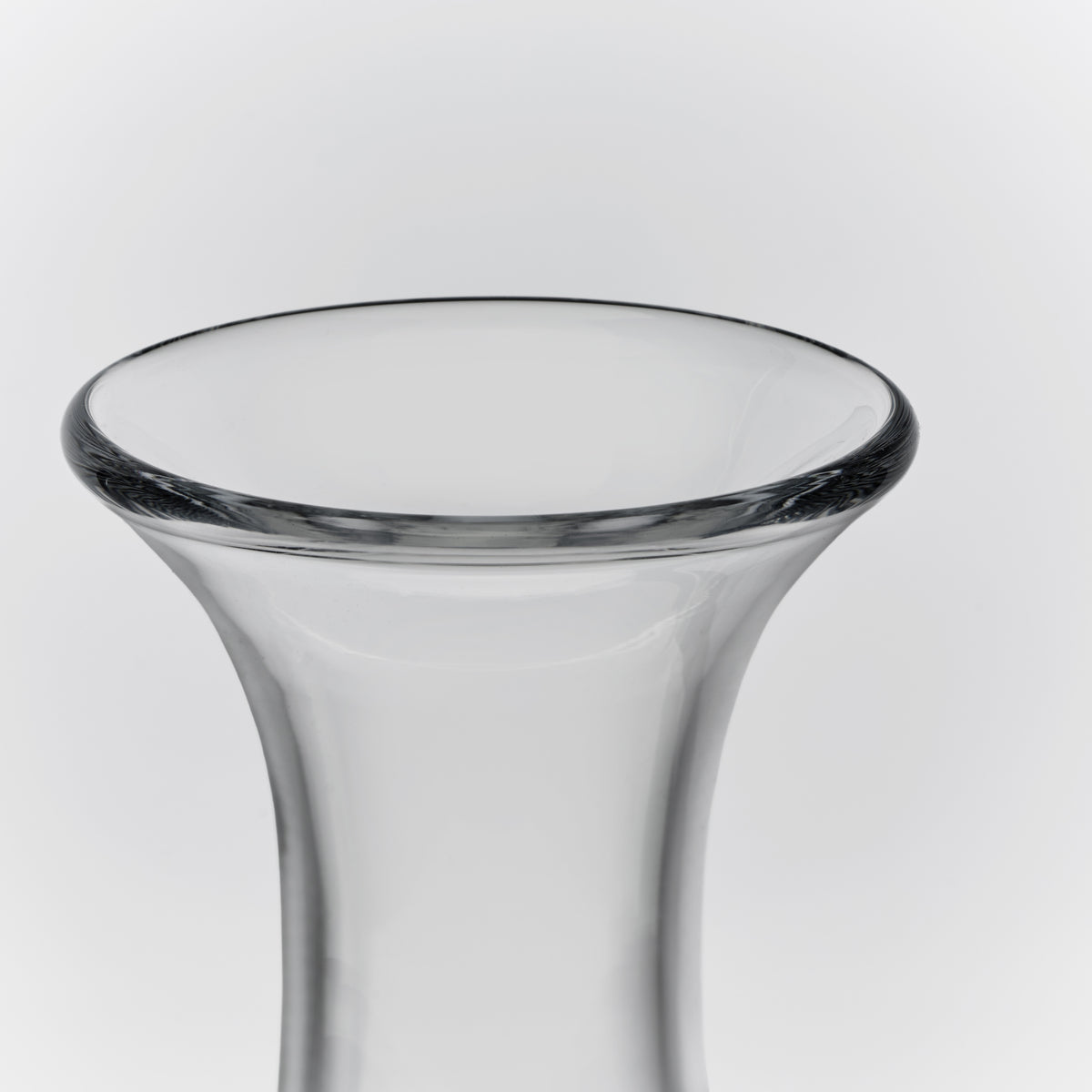 Clear glass wine decanter with a flared rim and tapered cylindrical body.