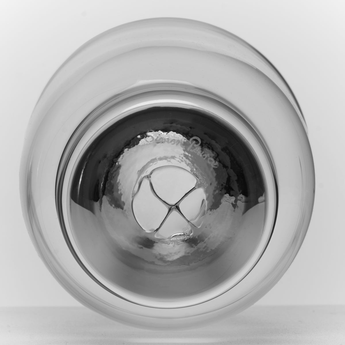 Clear glass tumbler with ice cubes inside, shown from above against white background.
