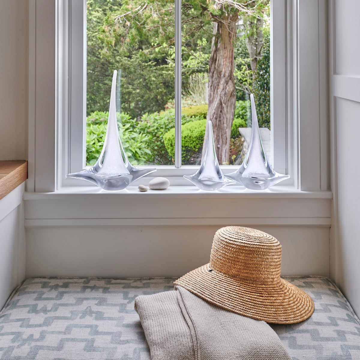 White sailboat sculptures displayed on a windowsill with decorative stones.