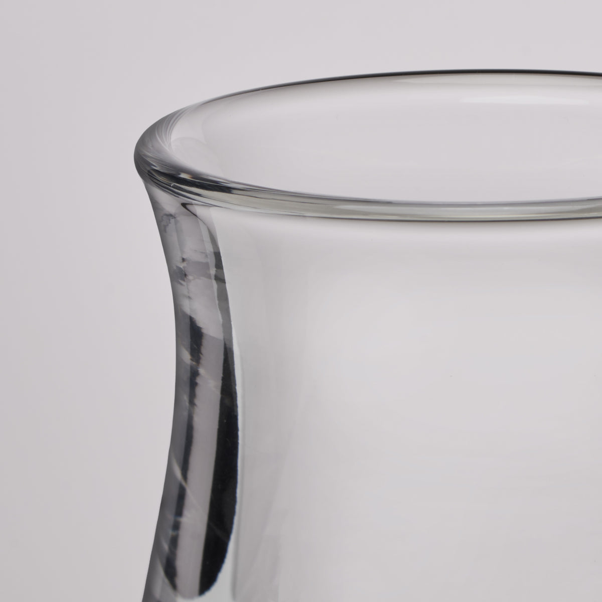 Close-up of a clear glass vase with a flared rim and smooth cylindrical body on a light gray background.