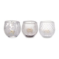 Three frosted glass tealight holders with varied textures containing cream-colored tealight candles.