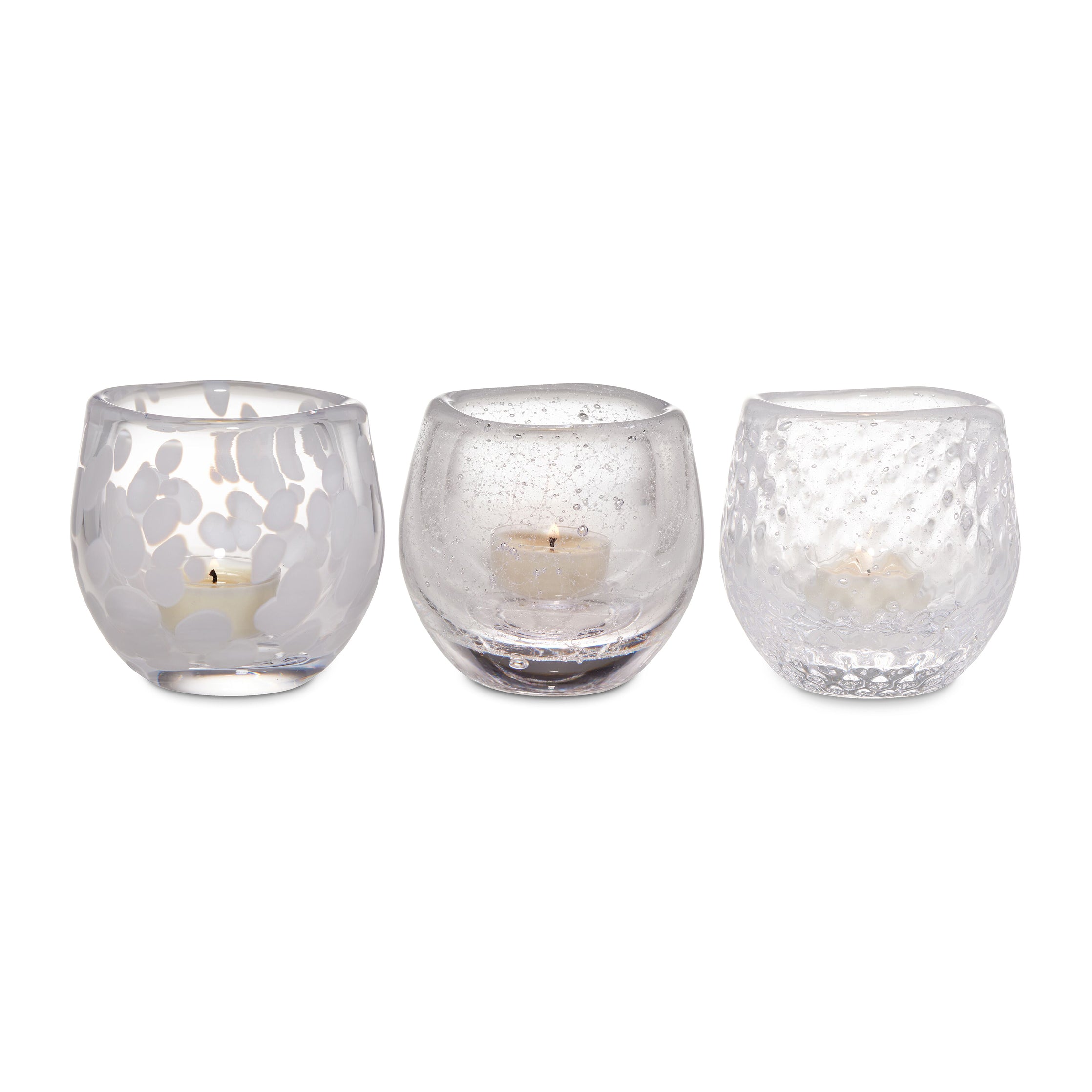 Three frosted glass tealight holders with varied textures containing cream-colored tealight candles.