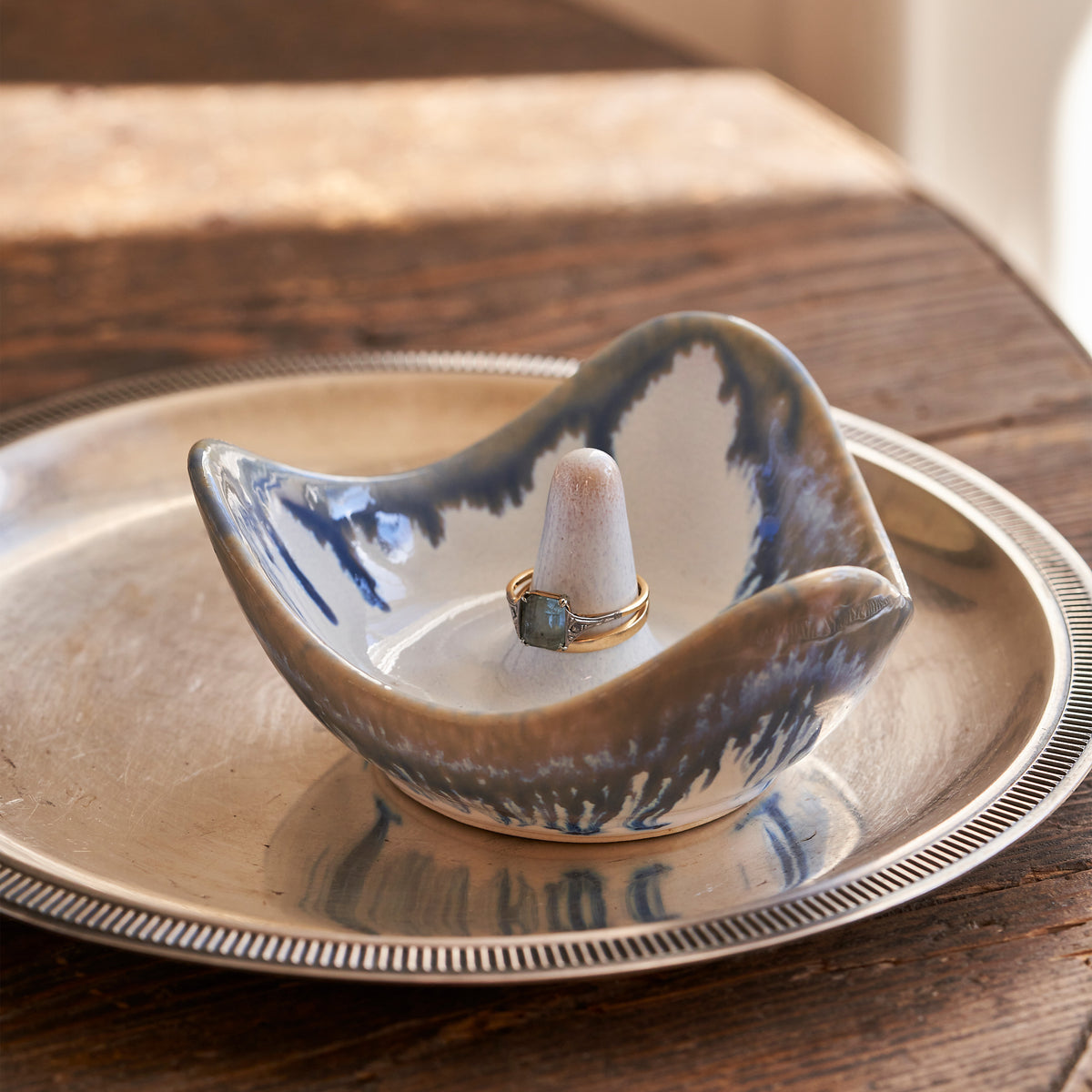 Blue and white ceramic ring holder with a small cone post, displayed on a matching plate.