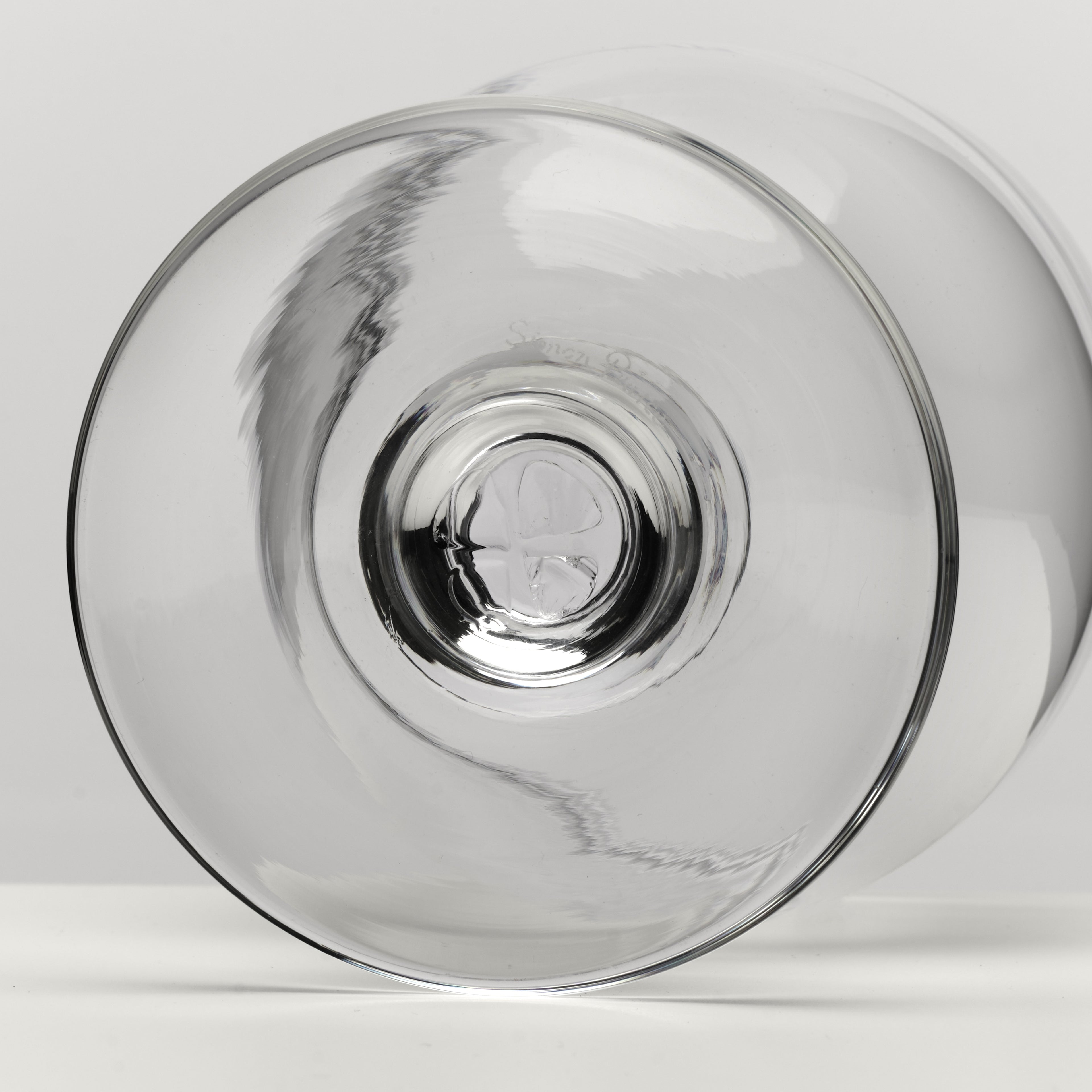 A clear glass bowl photographed from the bottom on a light gray studio background.