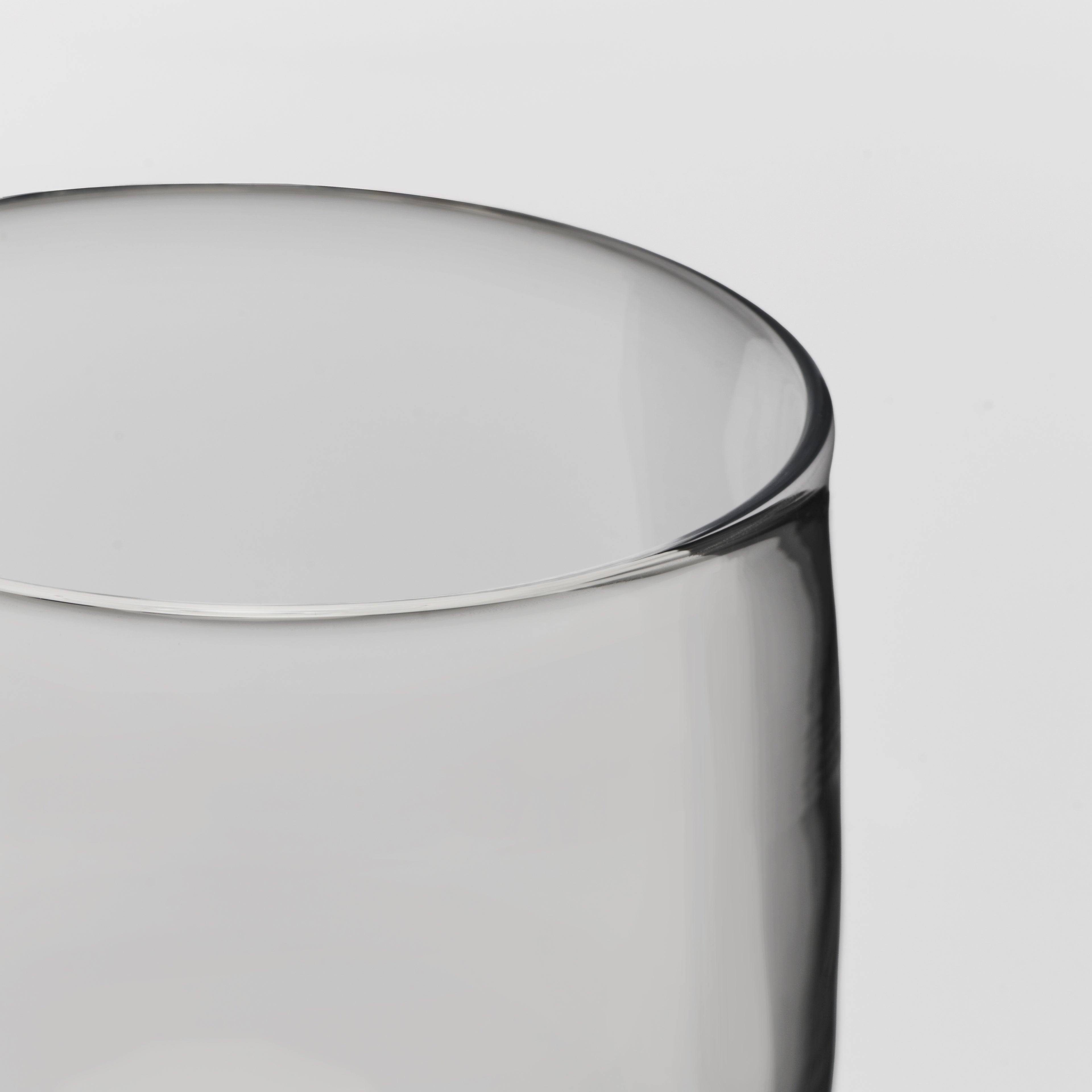 Close-up of a transparent glass showing the rim and body against a light gray background.