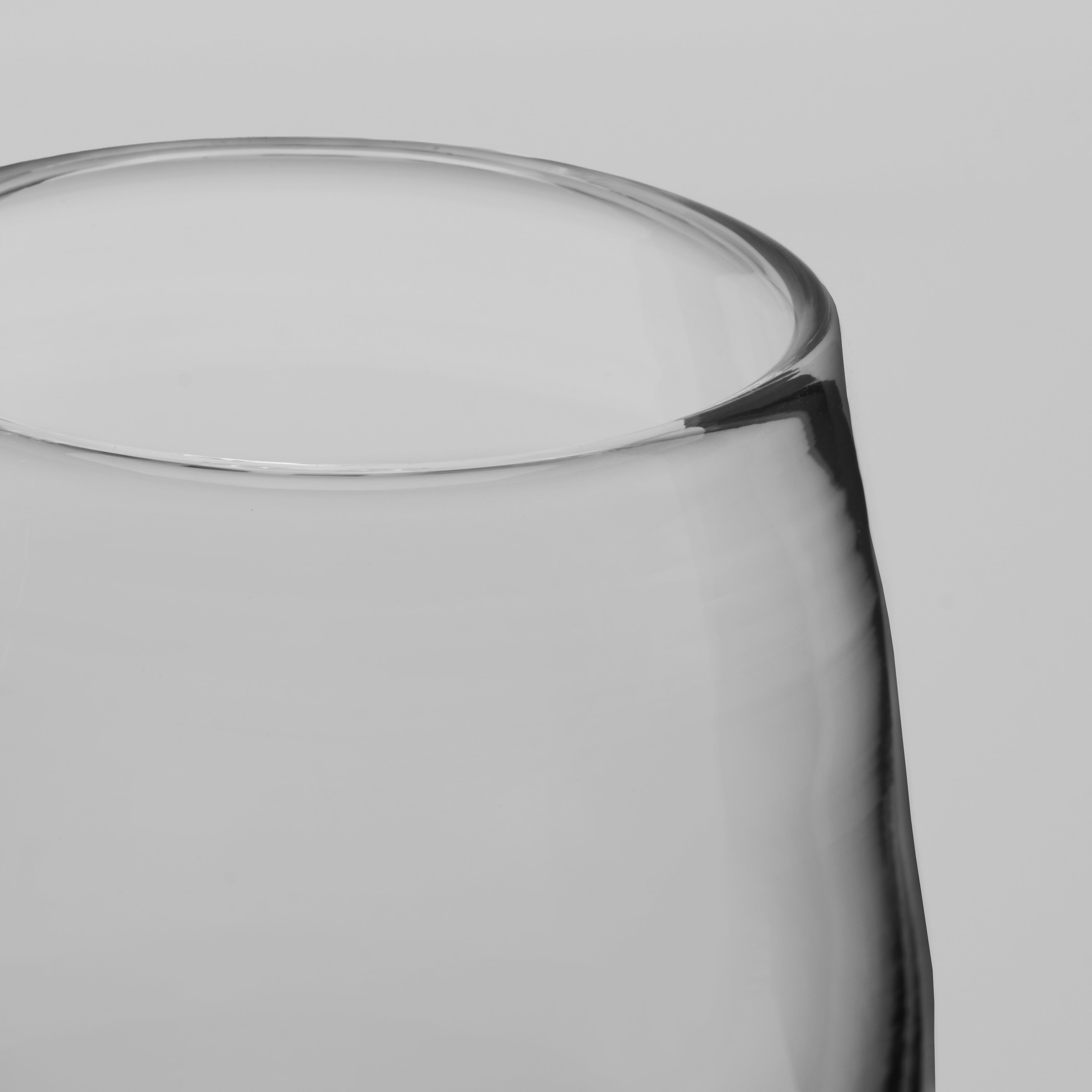 Close-up of a clear glass tumbler showing the rim and side profile against a light gray background.