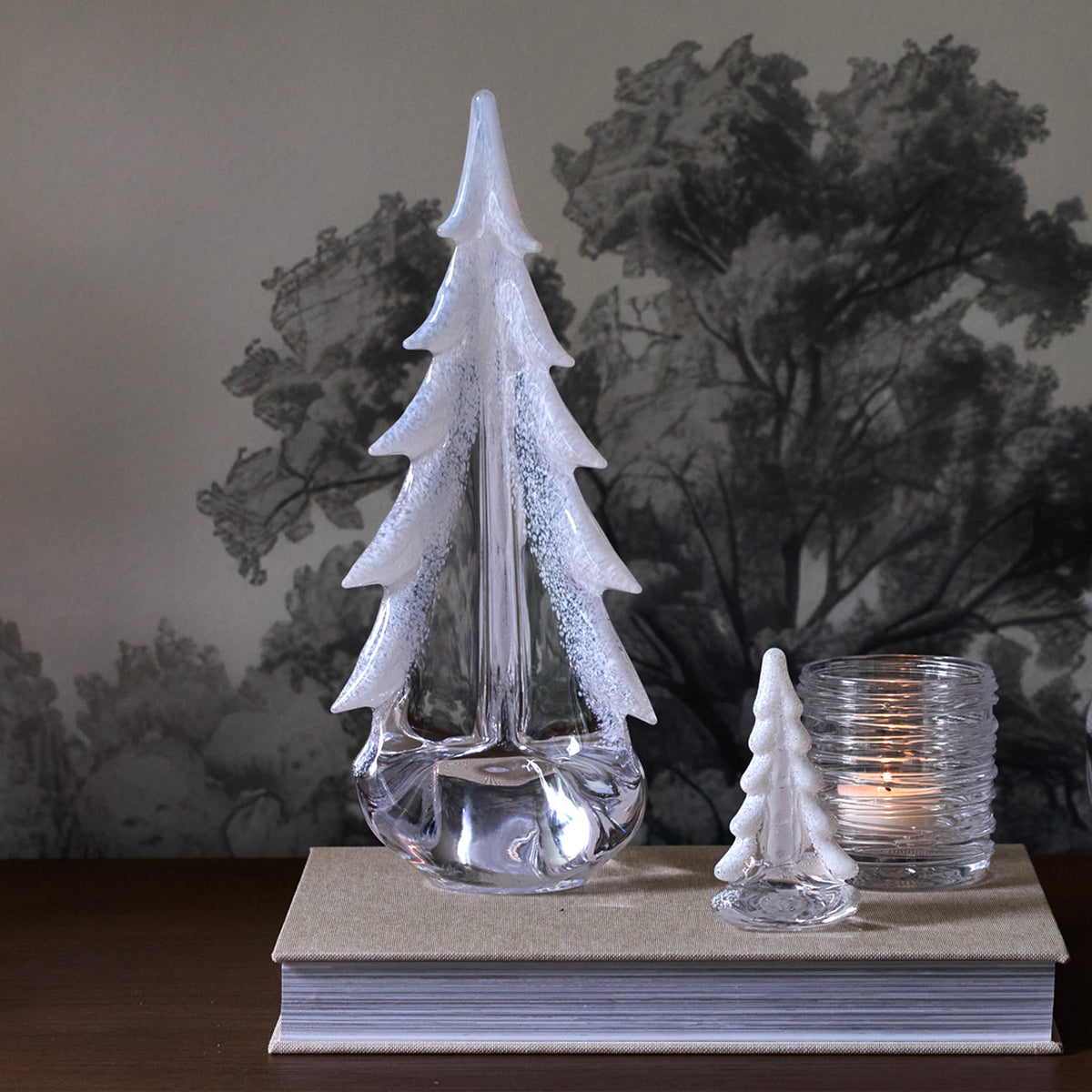 Clear glass tree-shaped decoration with white frosted coating, displayed with small tree figurine and candle on gift box base