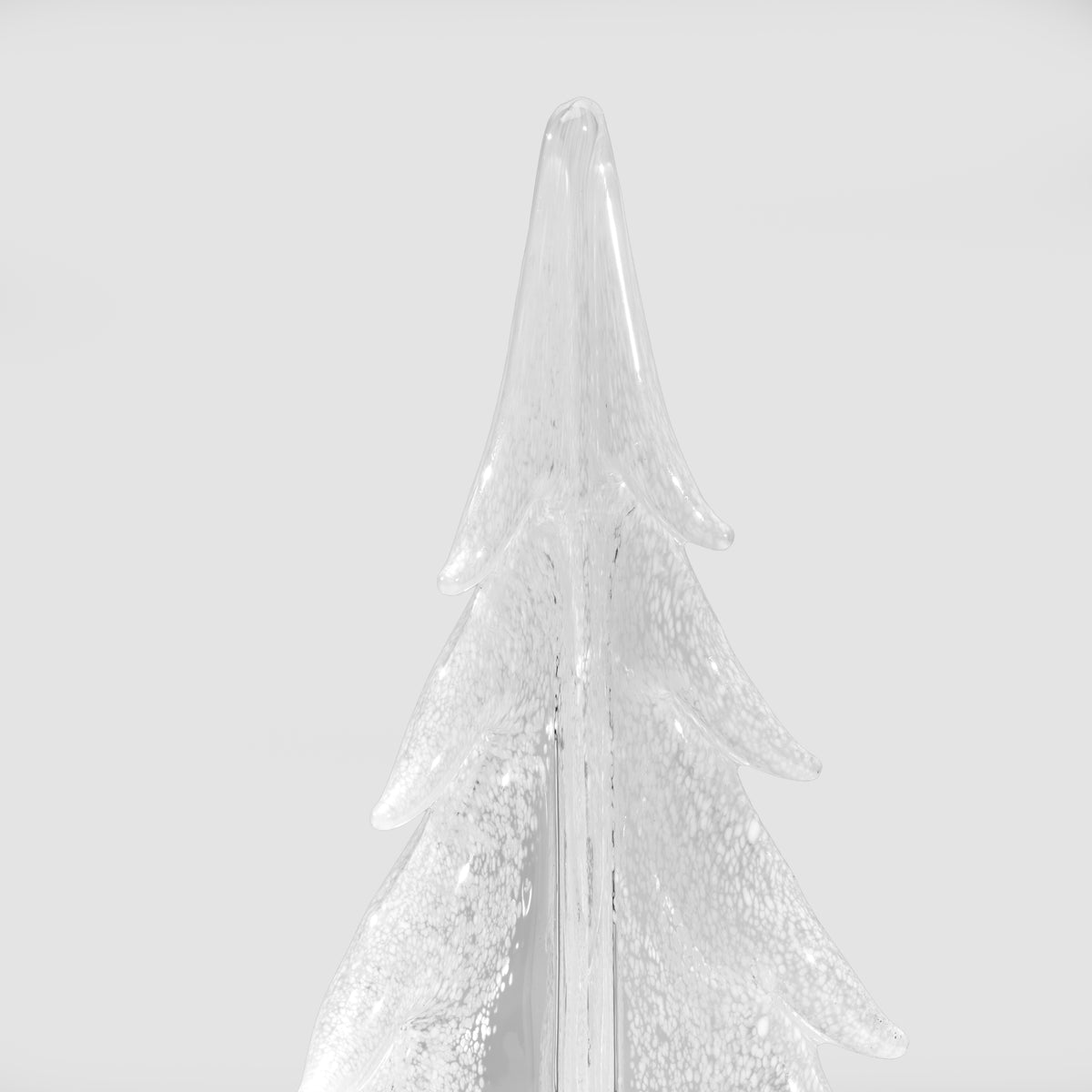 Clear glass evergreen tree decoration with white frosted coating and tiered branches, viewed from below against a light backg