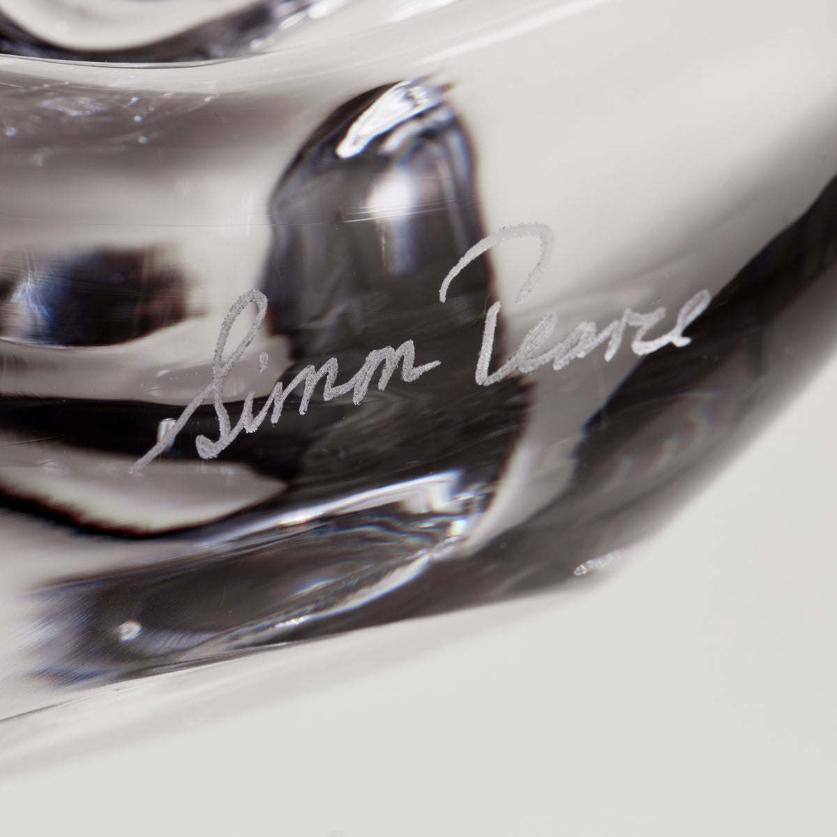 Clear glass sculptural tree with spiral design and artist signature etched on surface.