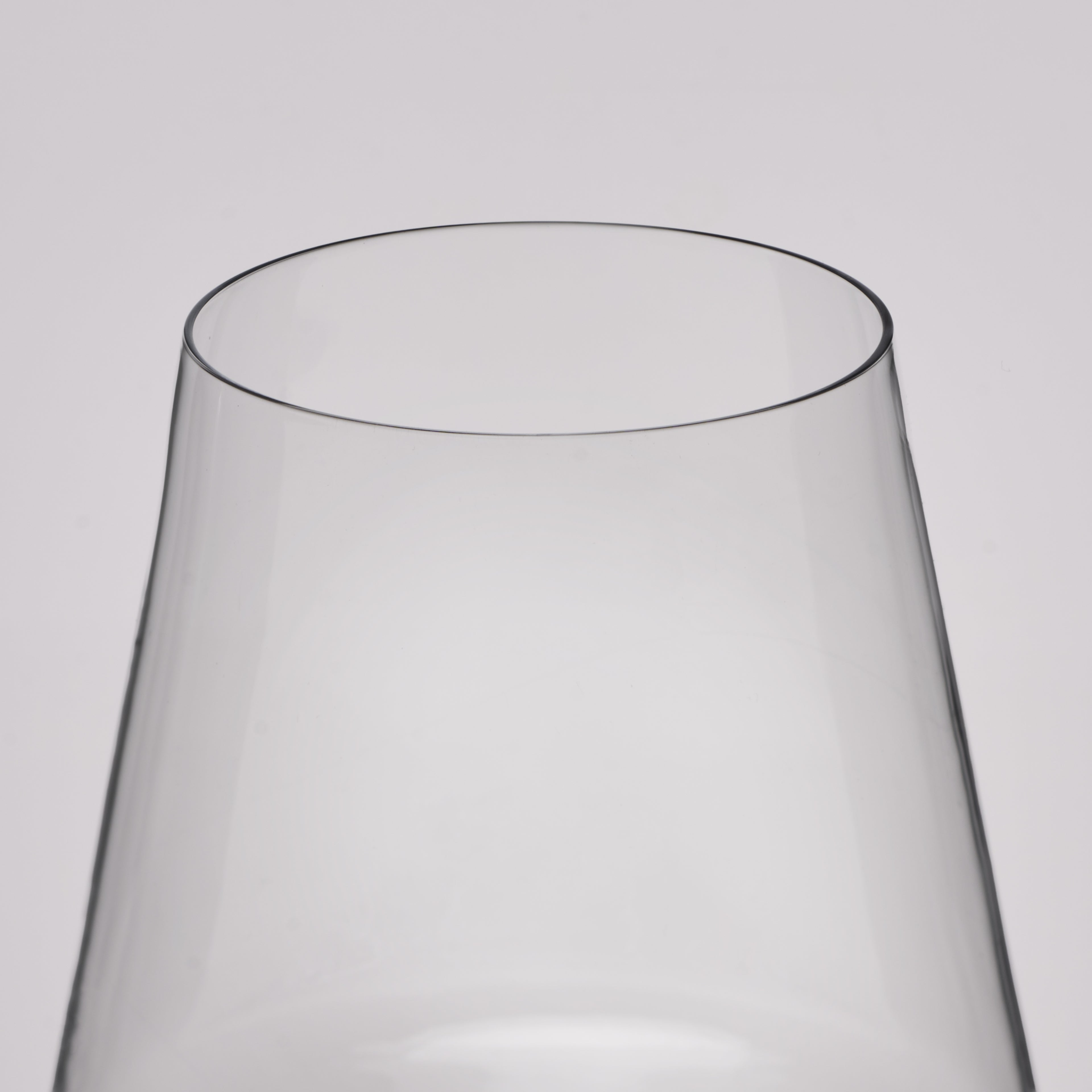 Close-up of a clear glass vessel, likely a wine glass or vase, showing the top rim and tapered transparent body against a light gray background.