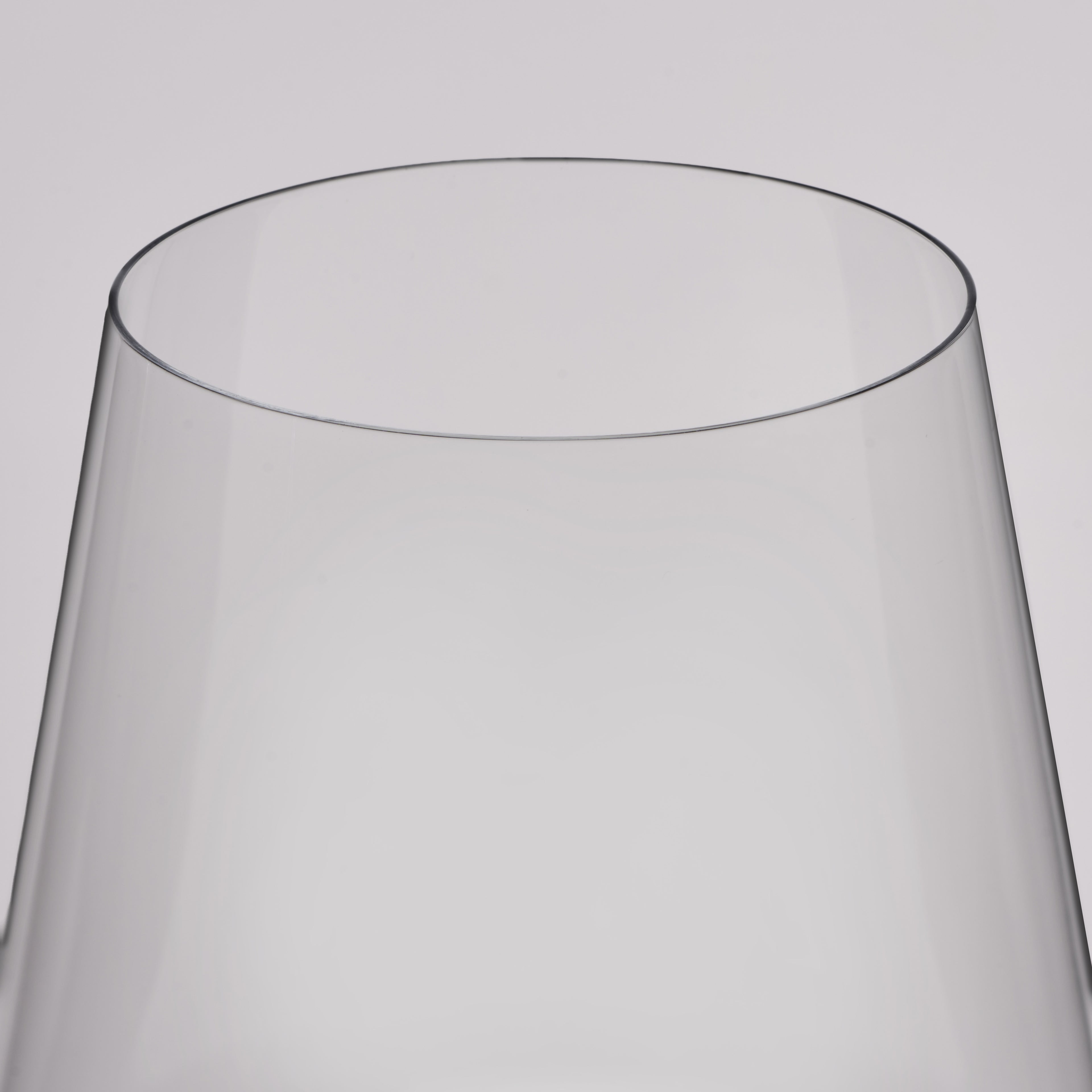 A close-up of a clear glass vessel, likely a wine glass, showing the smooth curved edge of its transparent body against a light gray background.