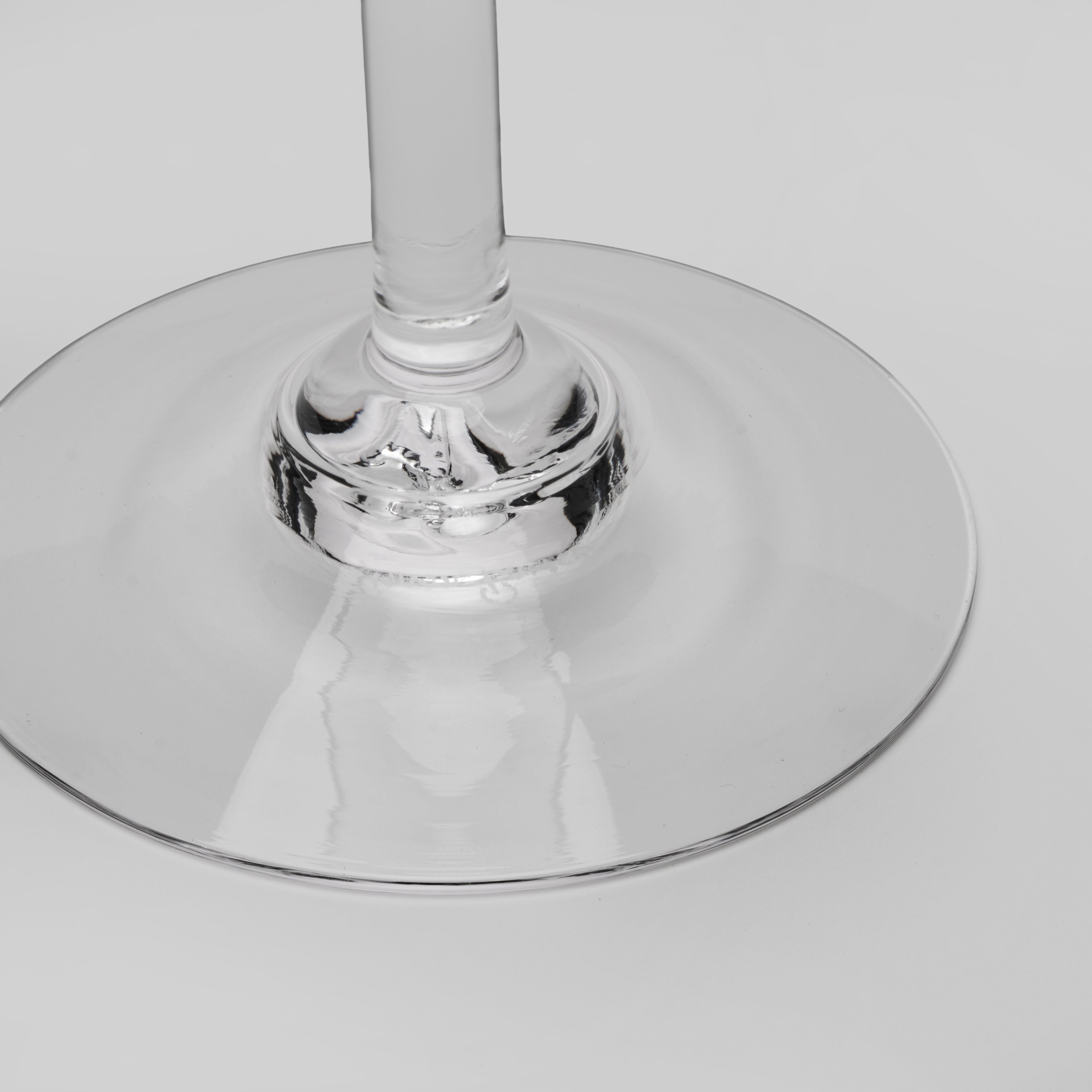Close-up of a clear glass wine glass base and stem on a light gray background.