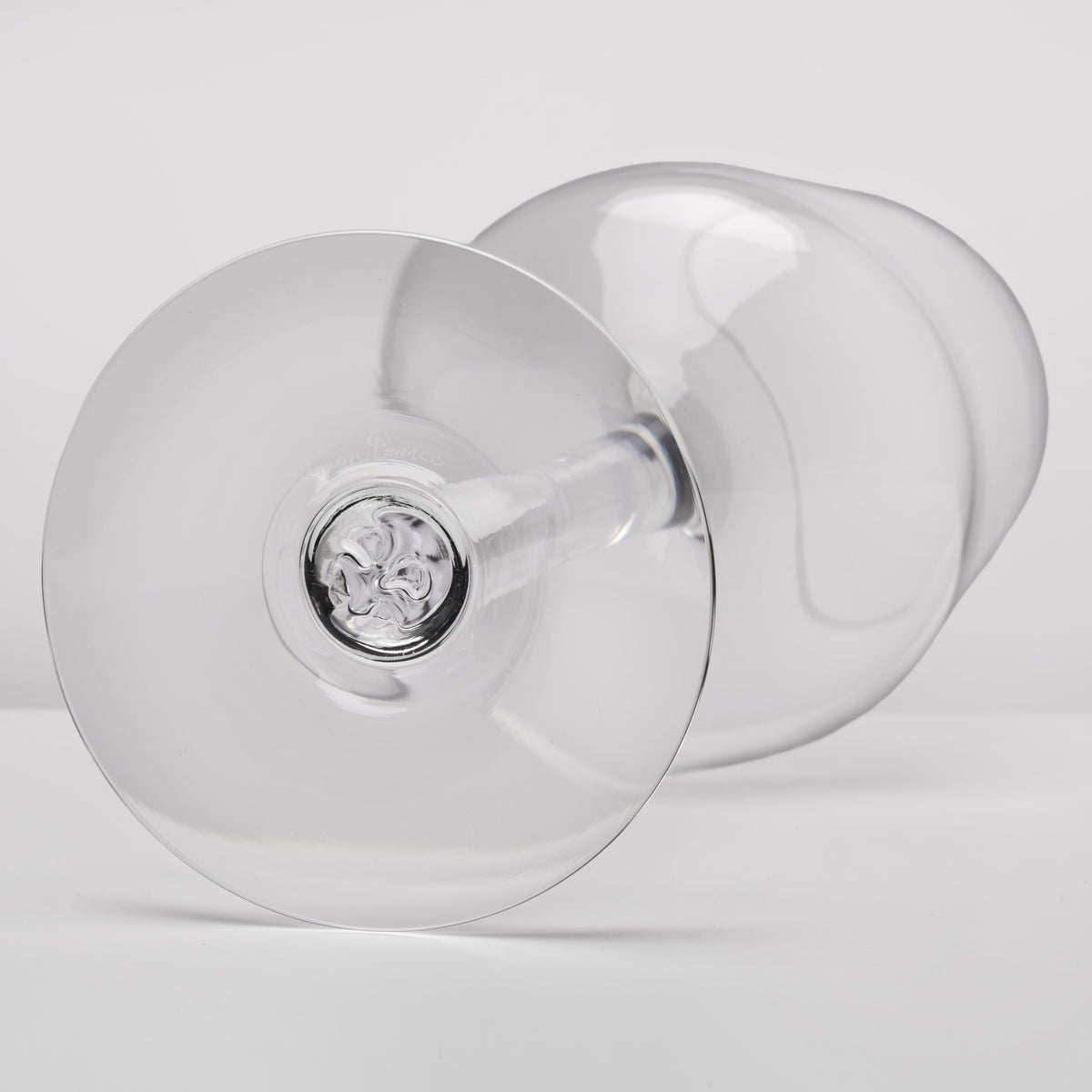 A clear glass wine glass shown from a side angle on a light gray studio background.
