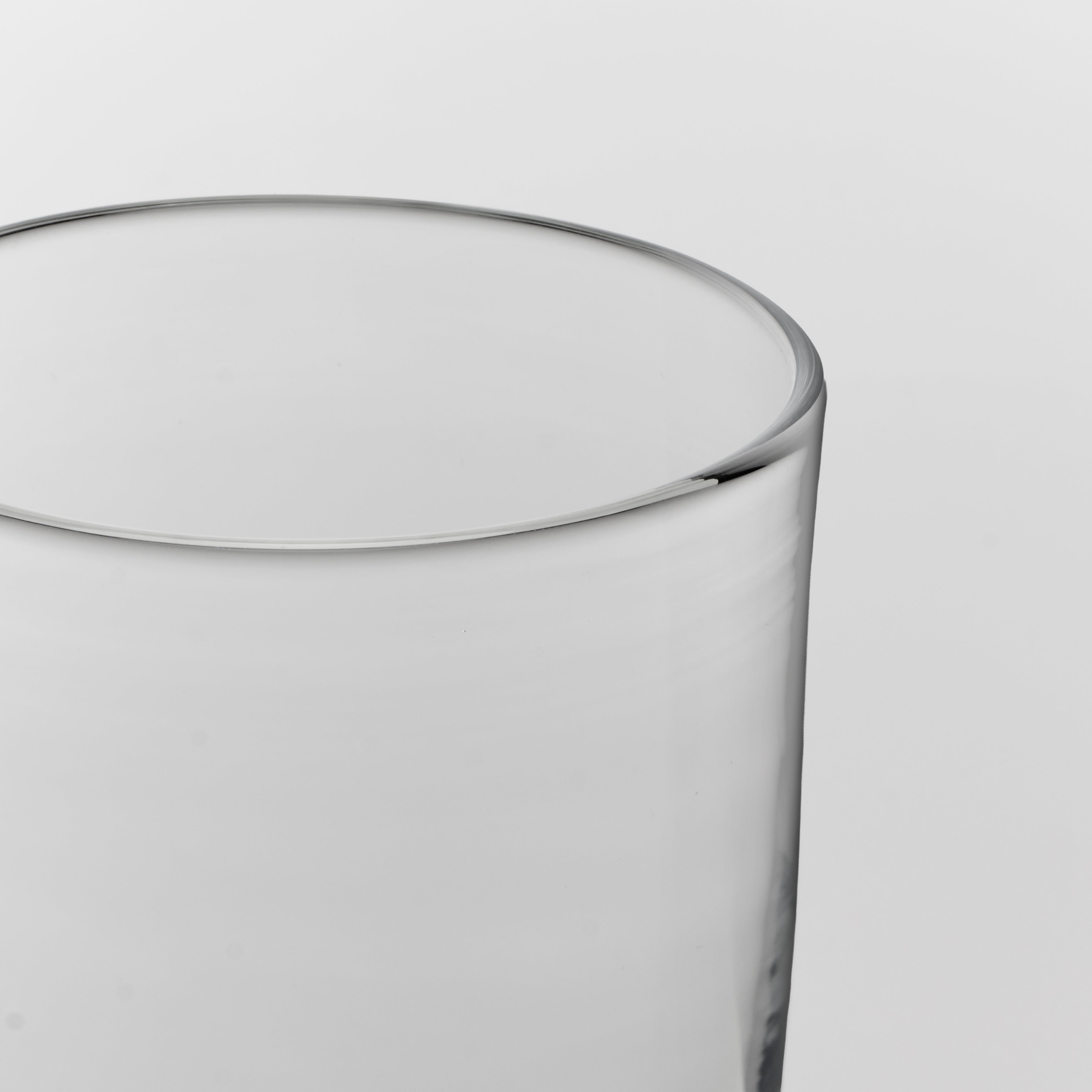 Close-up of a clear glass tumbler showing the rim and upper body against a light gray background.