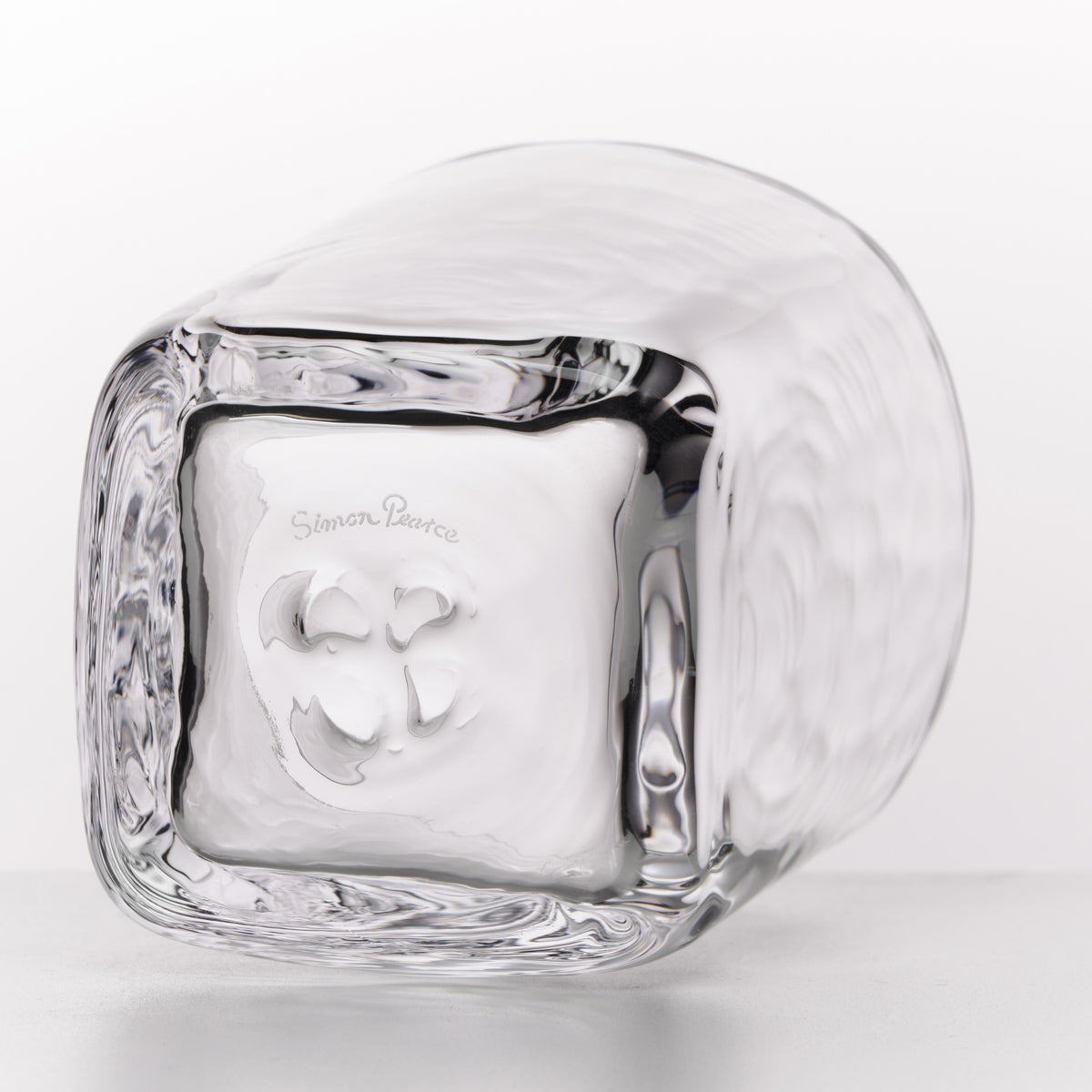 A clear glass block-shaped container with a textured outer surface and a smooth inner square compartment, photographed on a clean white background. The brand name 'Simon Paearce' is engraved on the outer surface.