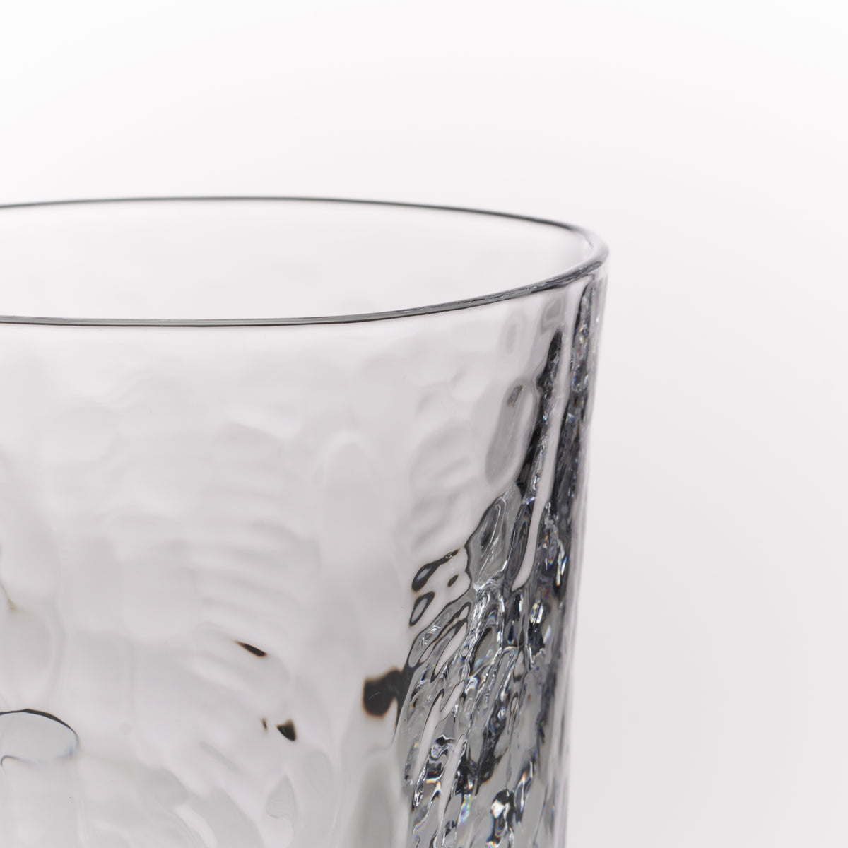 Close-up of a clear textured glass tumbler on a plain white background.