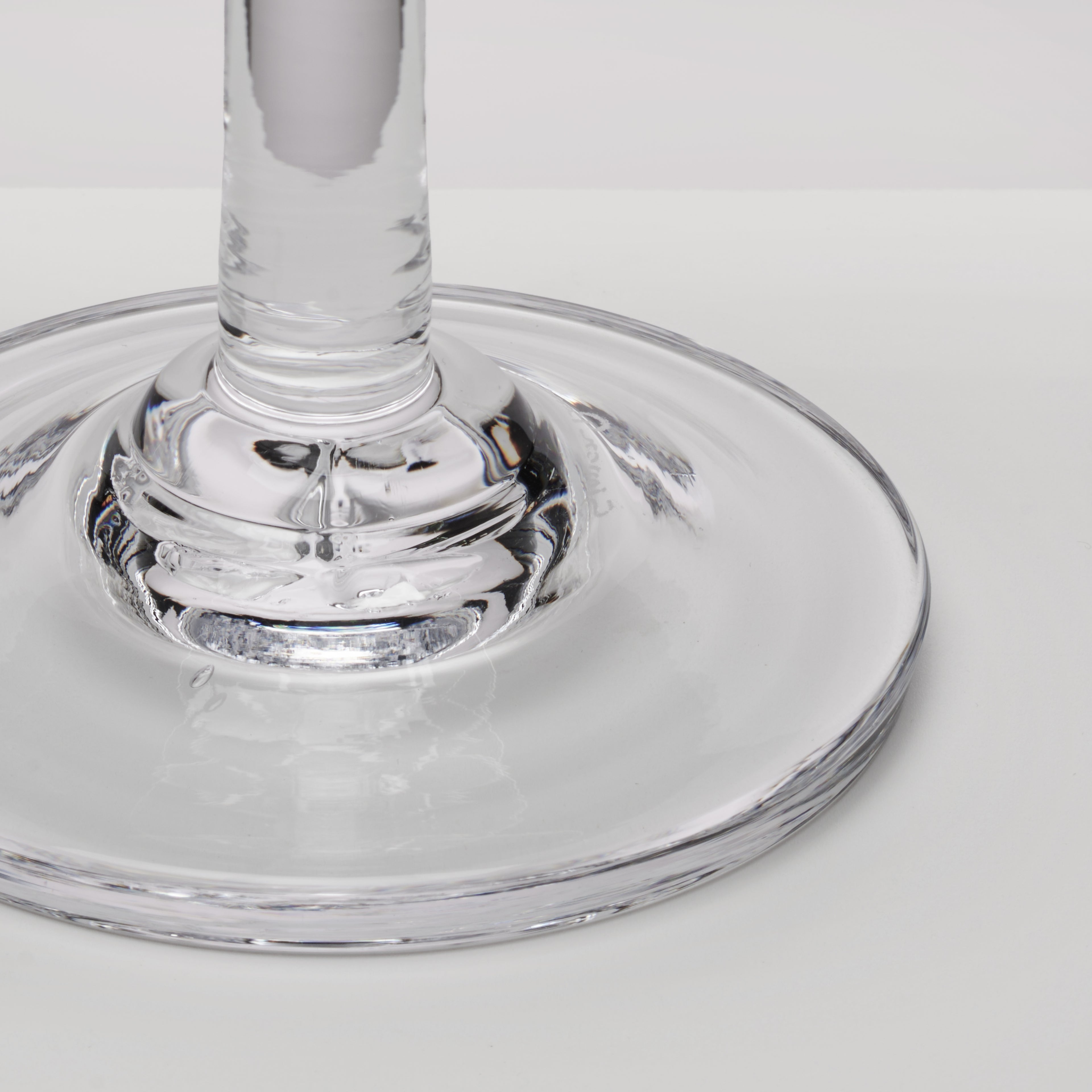 Close-up of a clear glass stem and circular base on a light gray background.