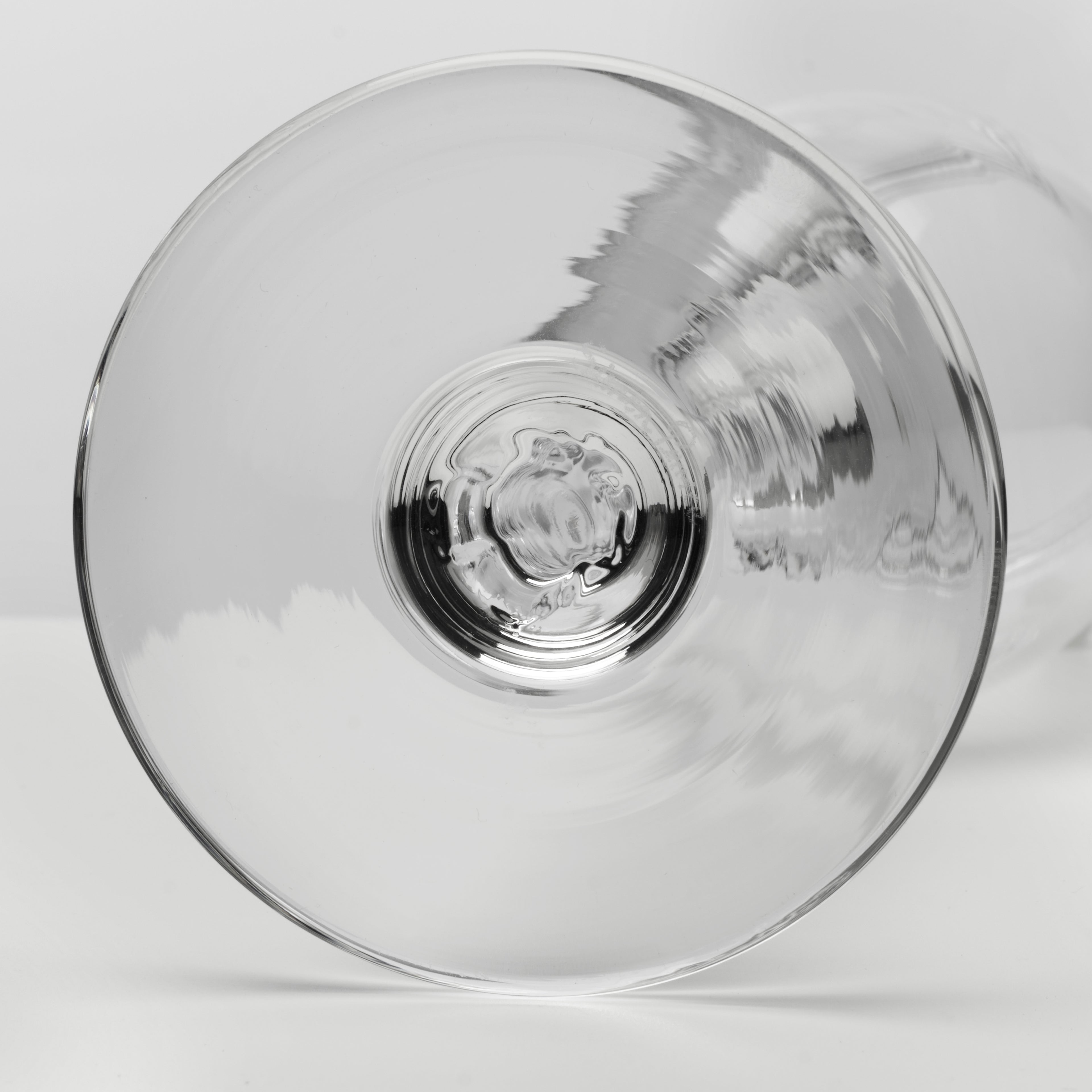 A clear glass wine glass viewed from the bottom, showing the circular bowl and a small portion of the stem against a light gray background.