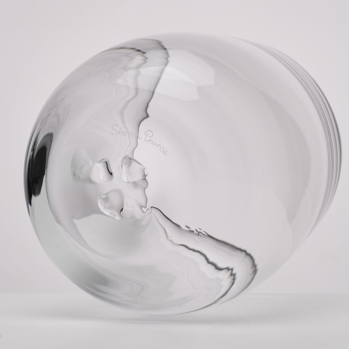 A clear glass photographed against a light gray studio background.