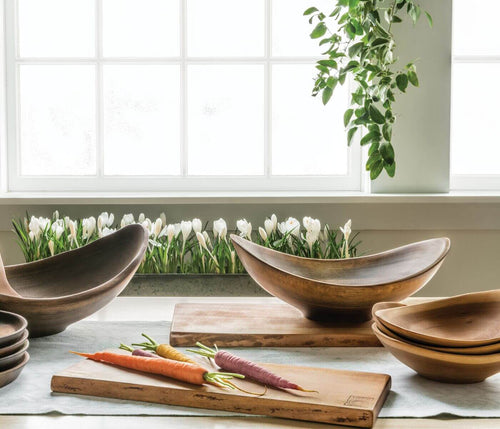 Cherry wood bowl with natural live edge, curved interior, displayed on windowsill with other wooden serving pieces.