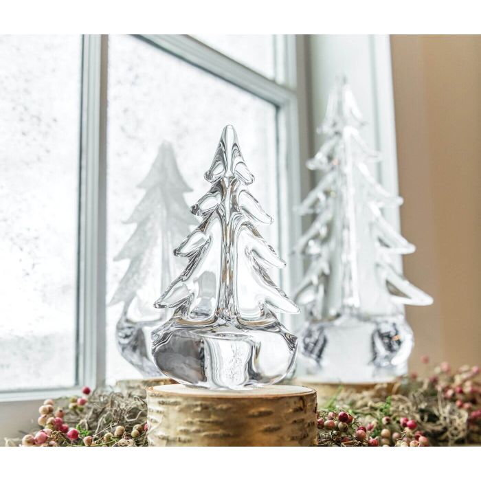 Three clear glass evergreen trees with wood-grain bases displayed on a windowsill with greenery.