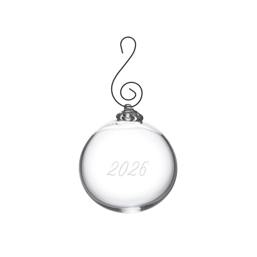 Clear glass round ornament with "2026" engraved on surface and metal scrolled hook hanger.