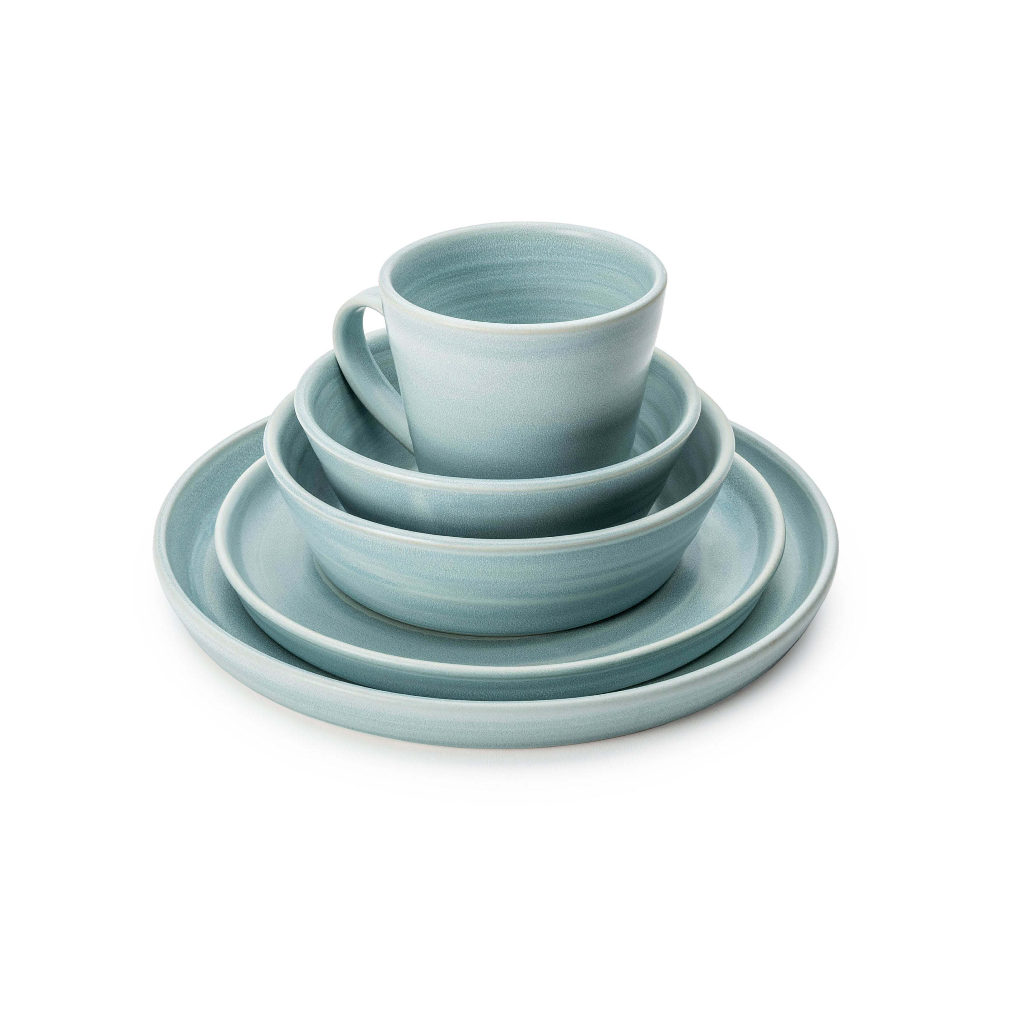 Light blue ceramic dinnerware set with mug, bowls, and plates arranged in graduated sizes.