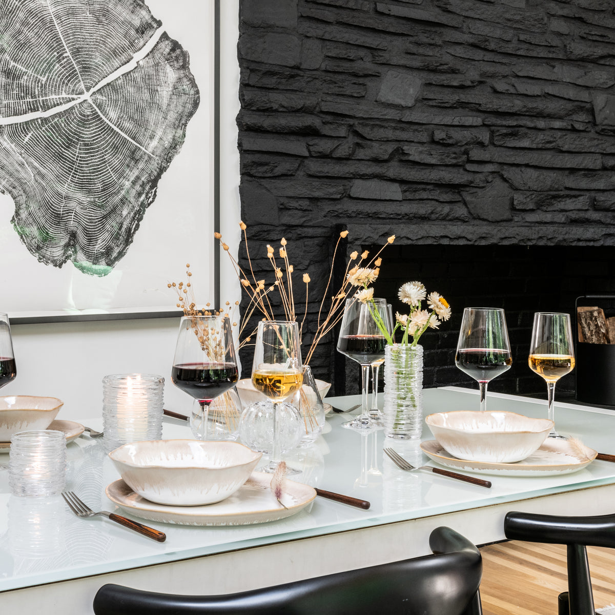 White ribbed dinnerware place settings with bowls and plates arranged on table with glasses and utensils.