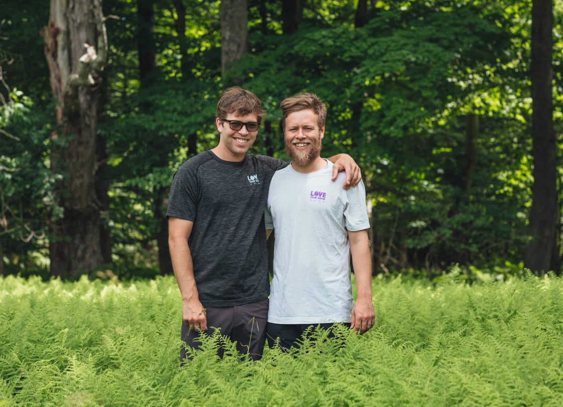 Kevin and Adam Pearce standing among ferns with a forested background