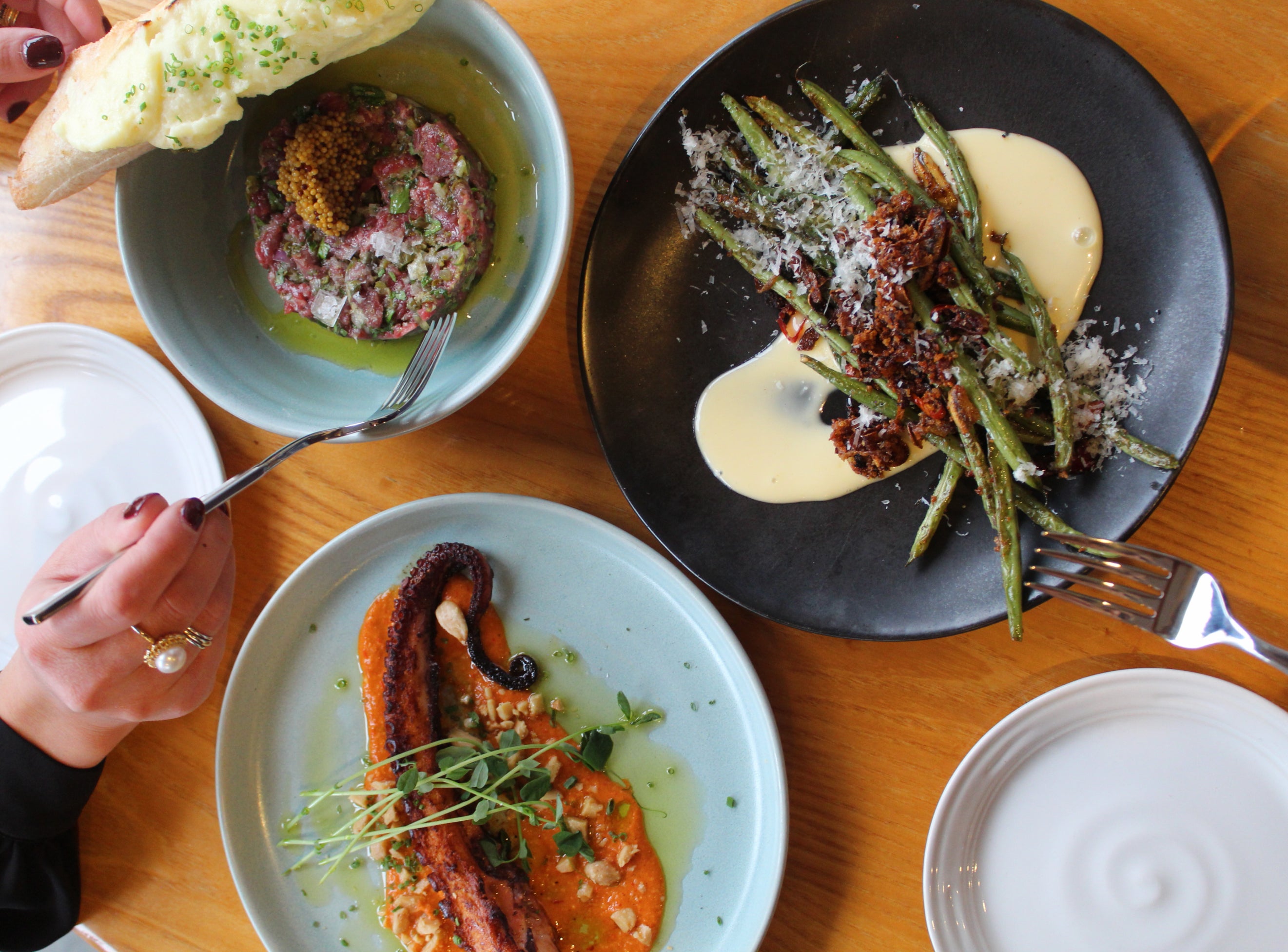 Overhead view of shared plates at Simon Pearce Restaurant, including beef tartare, charred green beans, and grilled octopus