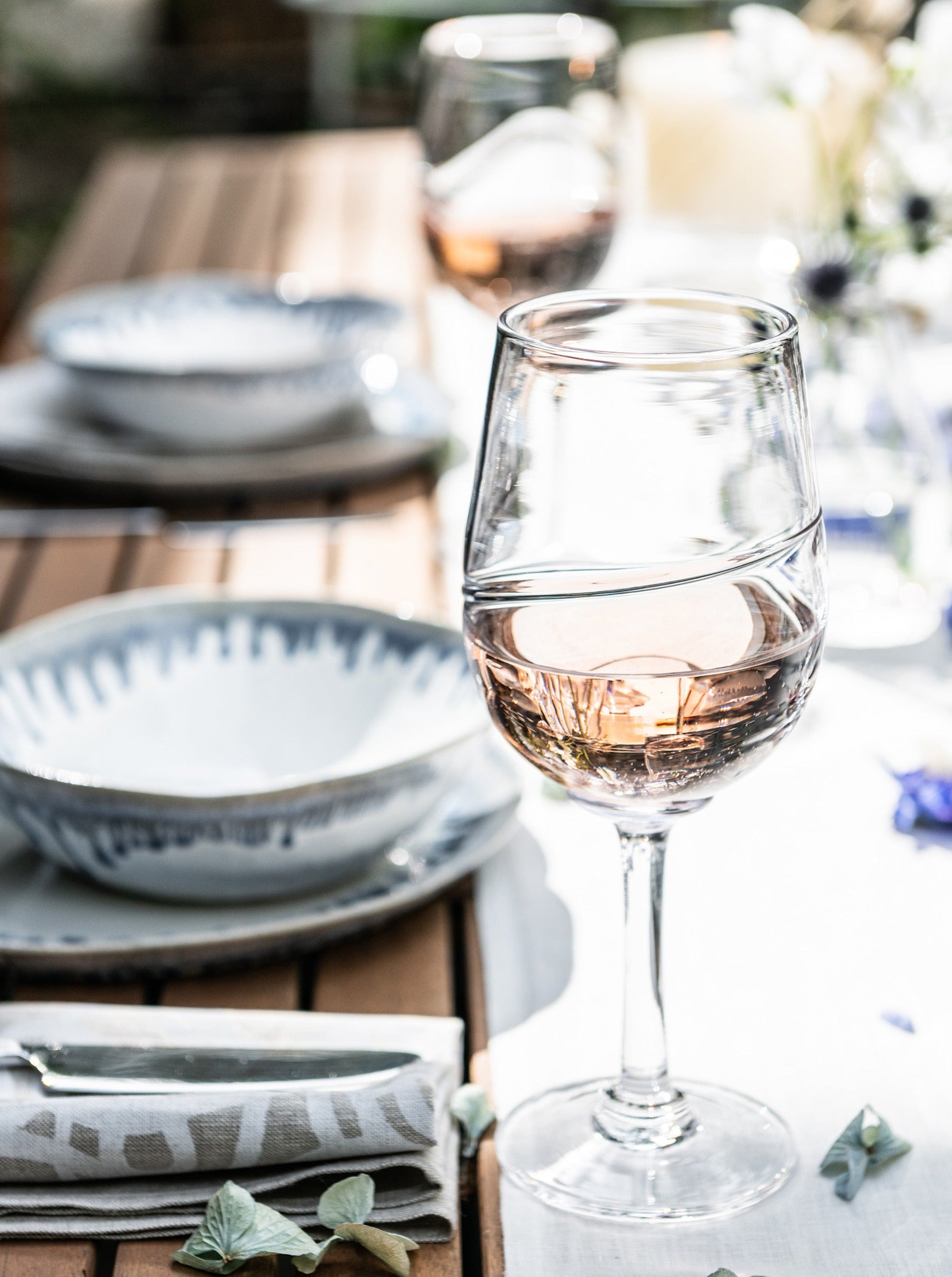 Glass of red wine on a formal dining table setting with plates and place settings.