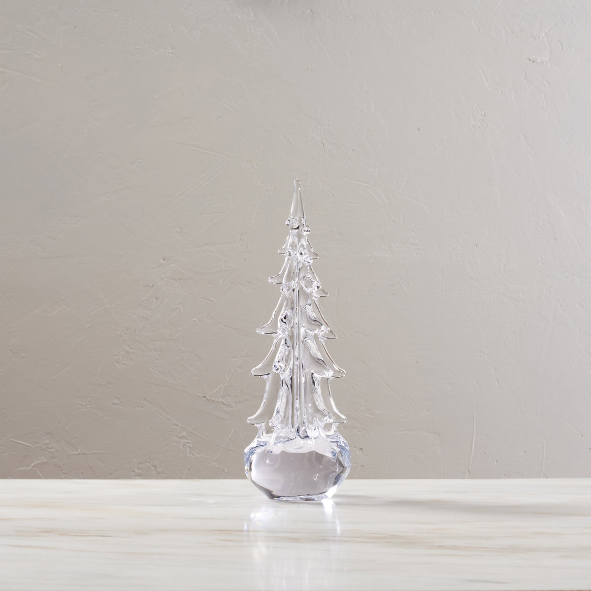 Clear glass evergreen tree ornament with pointed top and tiered branches on rounded base.