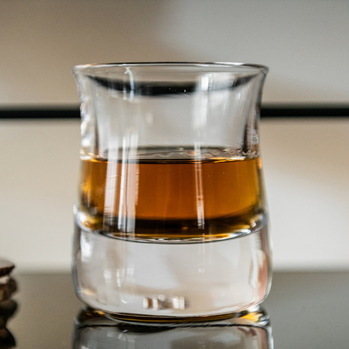 Clear glass tumbler filled partially with amber whiskey, featuring horizontal band design.