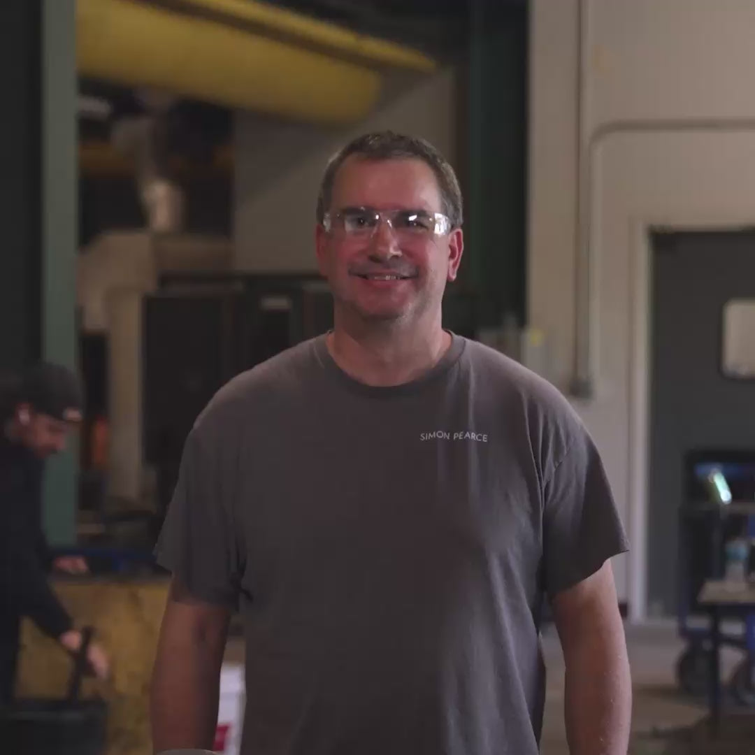 Closeup shot of one of the glassblowers at Simon Pearce smiling at the camera