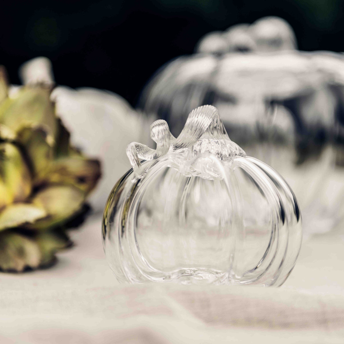 Three clear glass pumpkin-shaped vessels in varying sizes arranged on white surface.